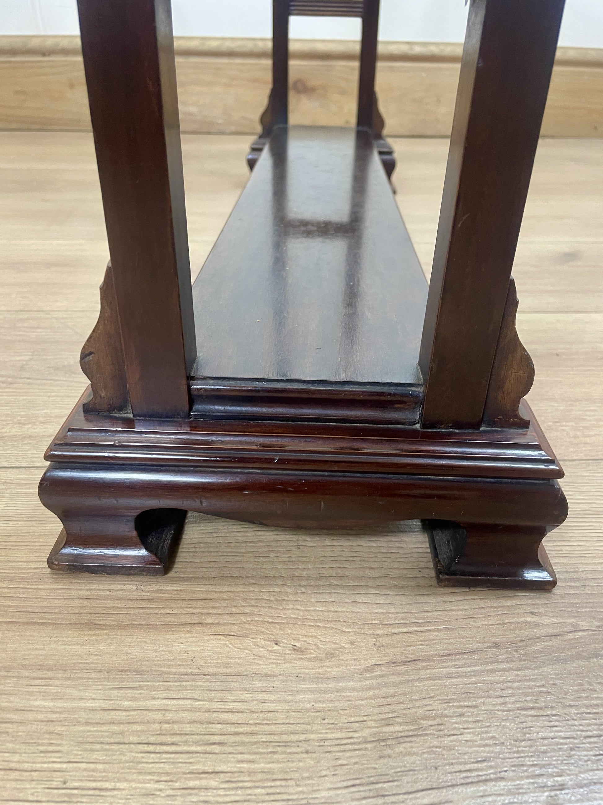 Wooden display stand with glass top on a wooden floor