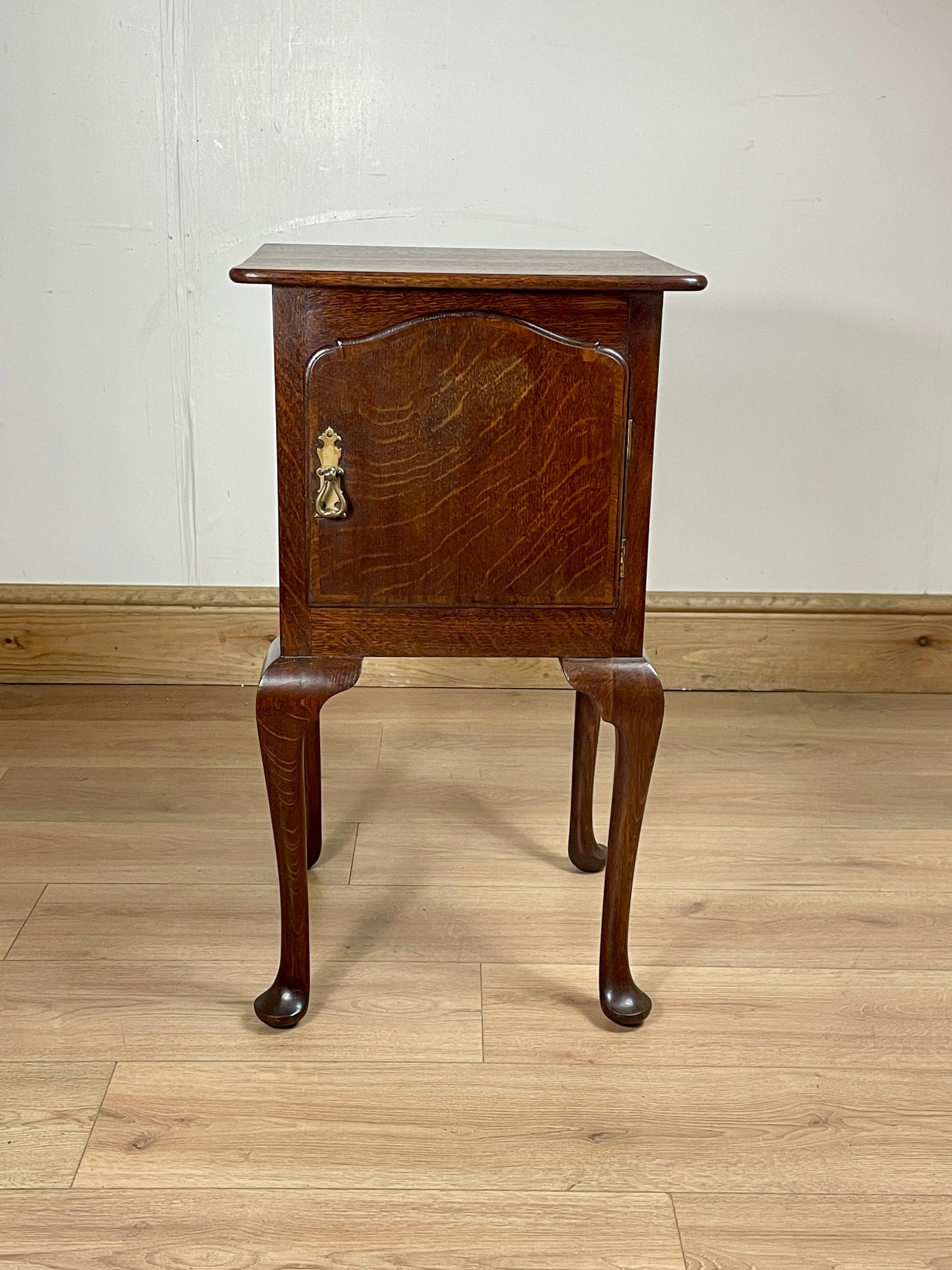 Wooden side table with a marble top on a wooden floor.