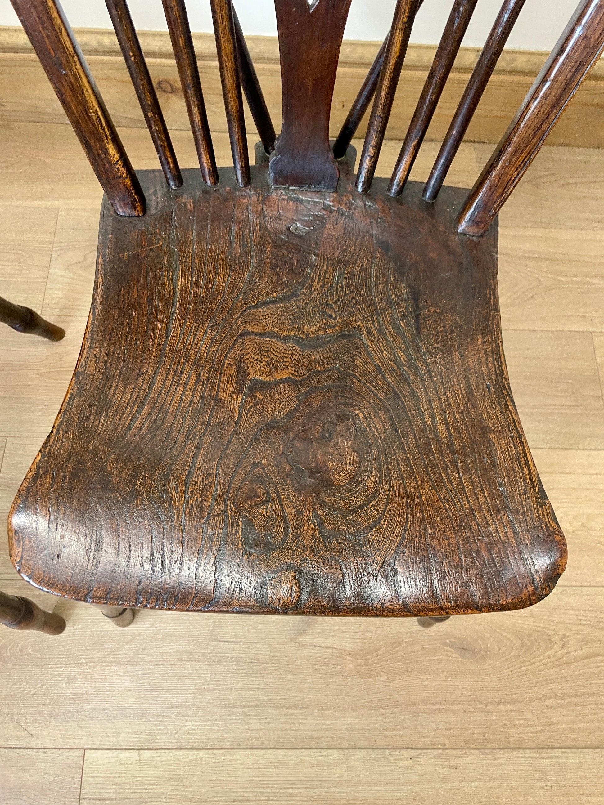 Wooden chair seat with visible wear on a wooden floor
