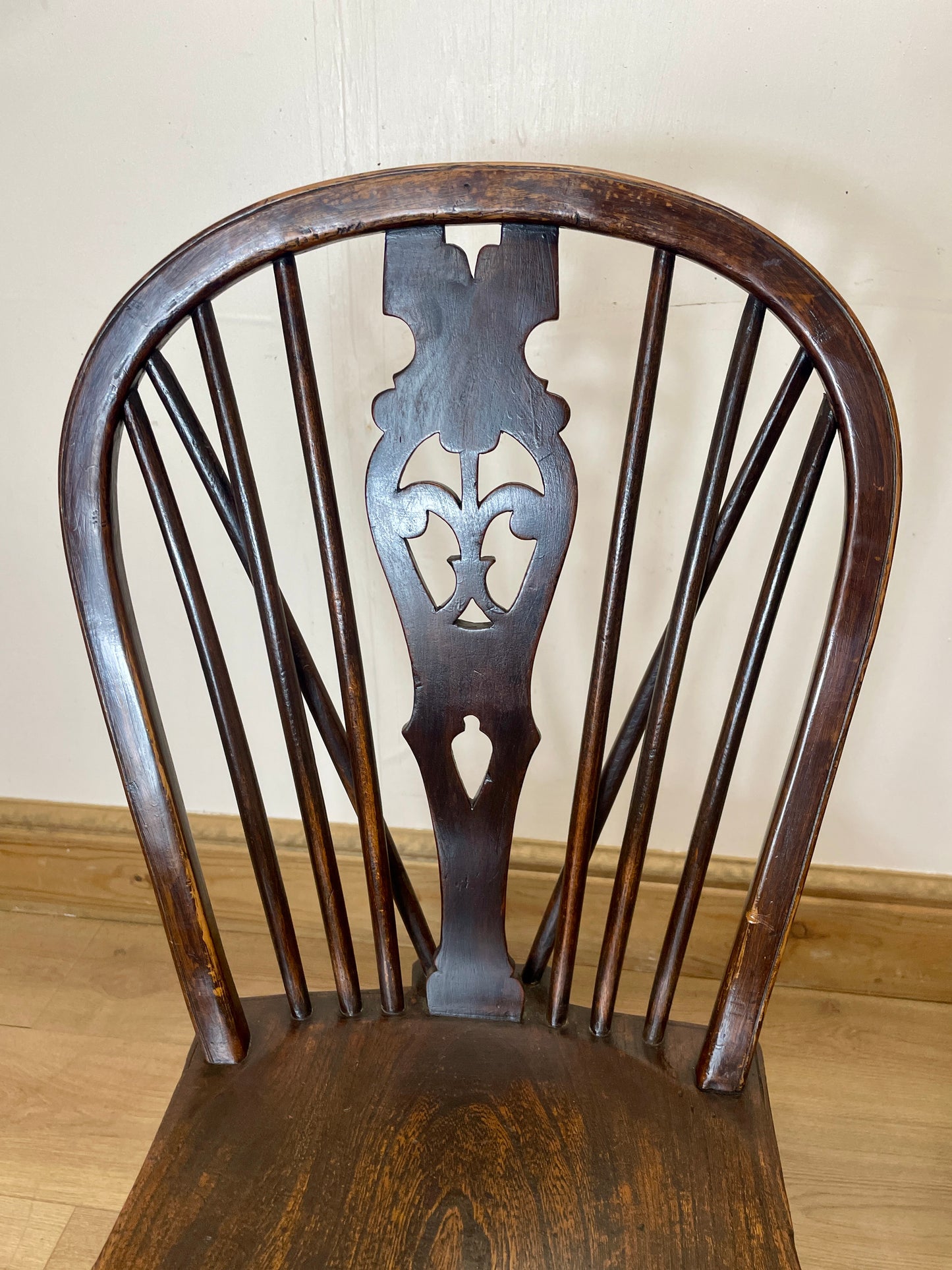 Wooden chair with intricate back design on a wooden floor.