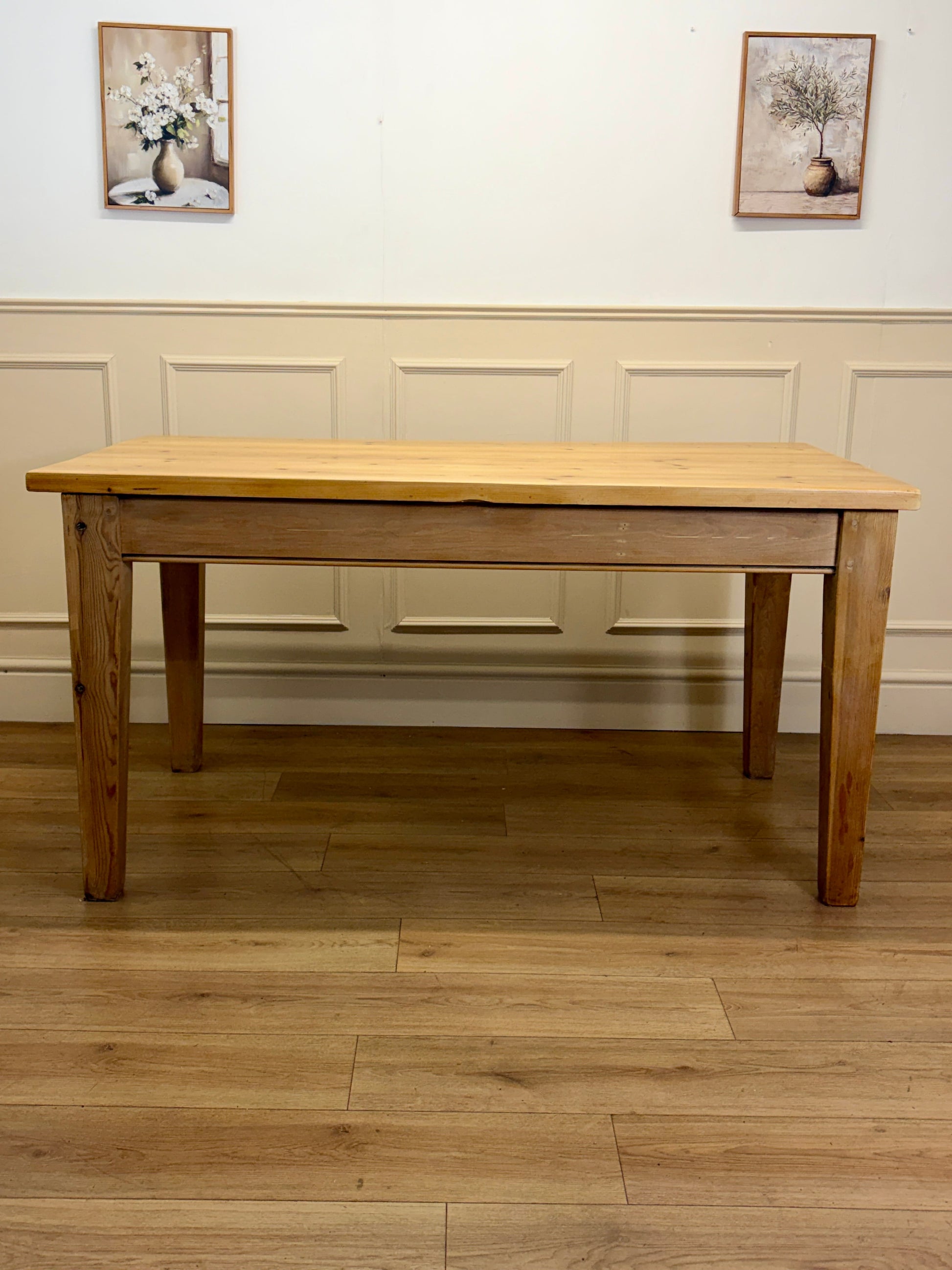 Wooden dining table in a room with wooden flooring and white walls.