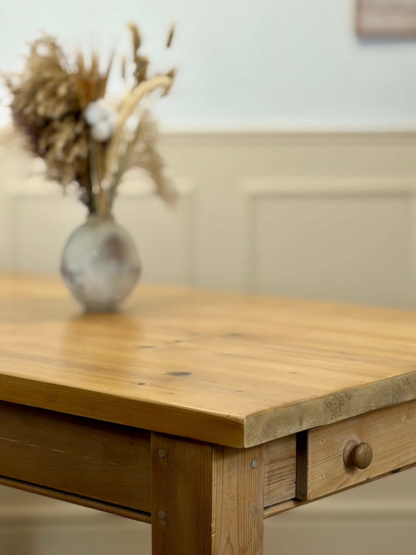 Wooden table with a vase of dried flowers on a neutral background