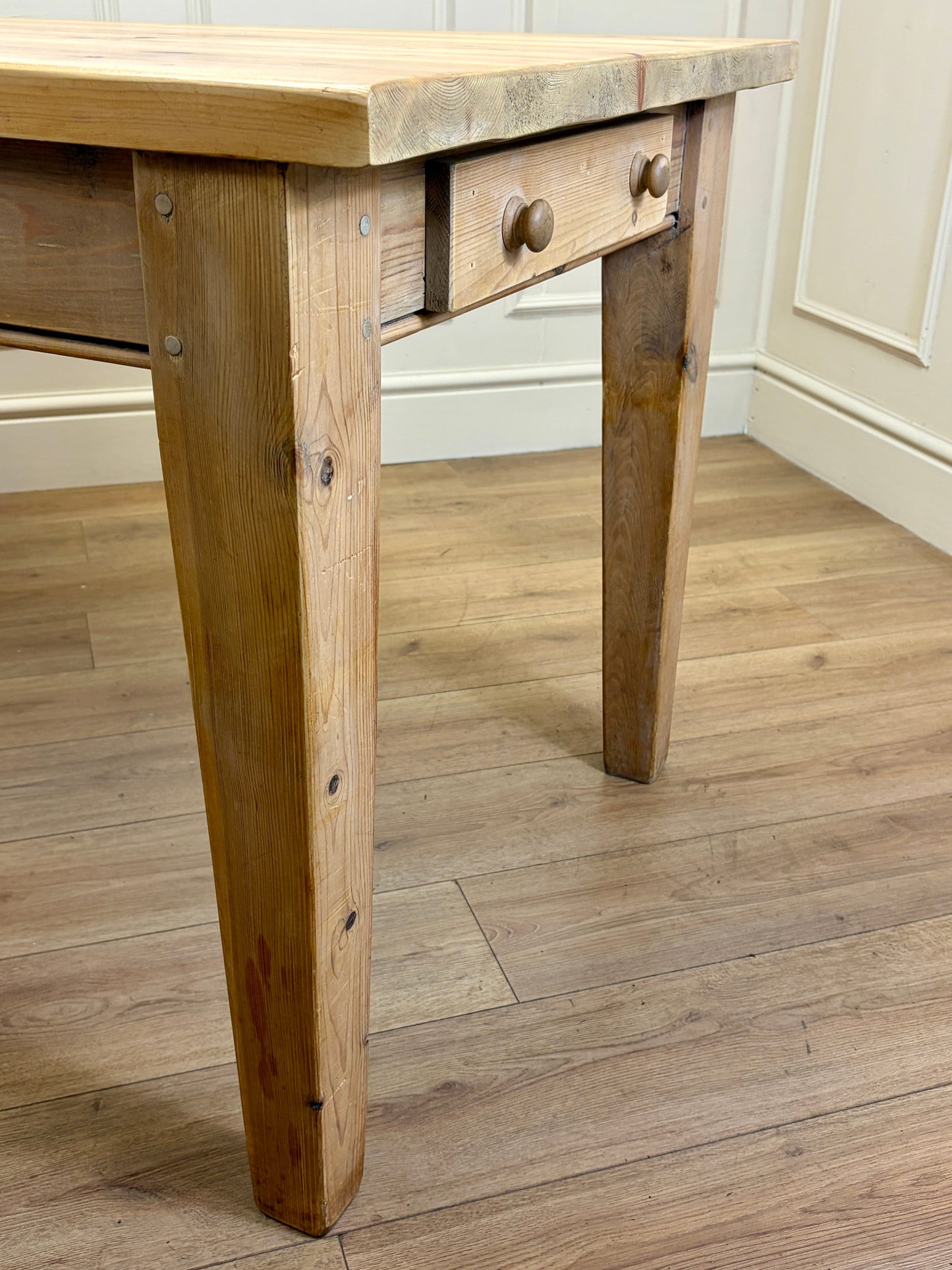 Wooden table with a single drawer on a wooden floor.