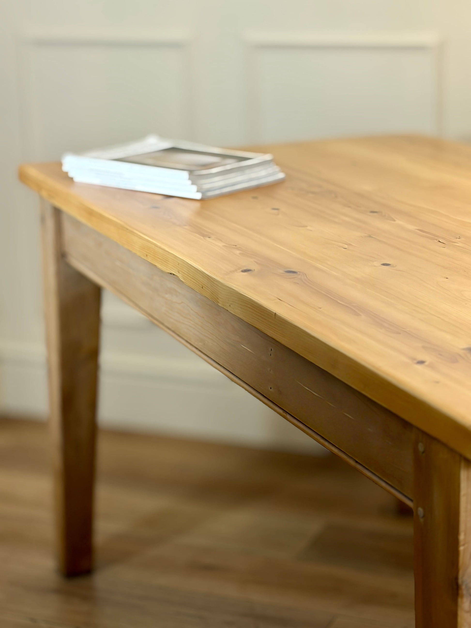 Wooden table with a stack of books on a wooden floor.