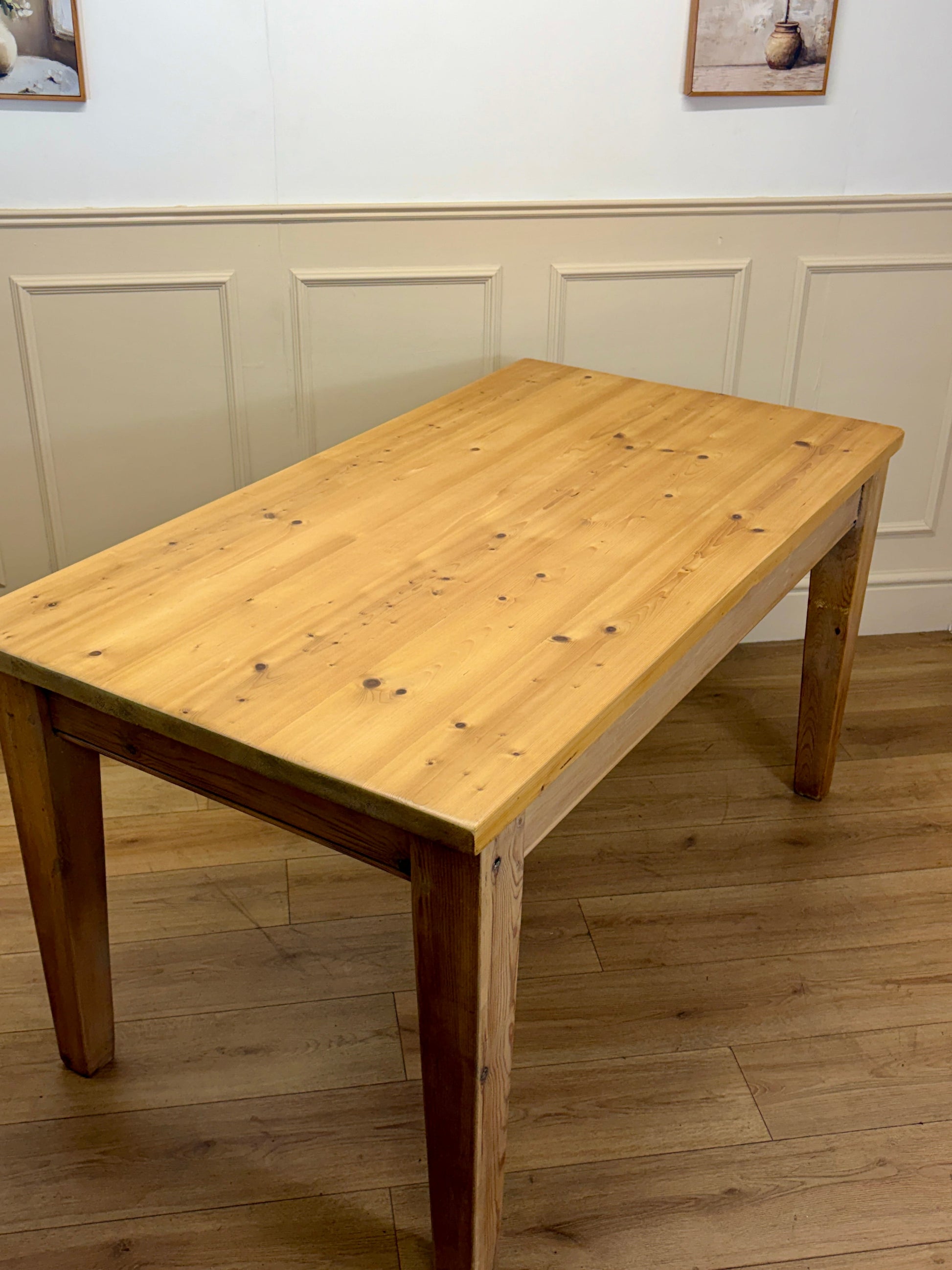 Wooden dining table in a room with panelled walls and wooden flooring.