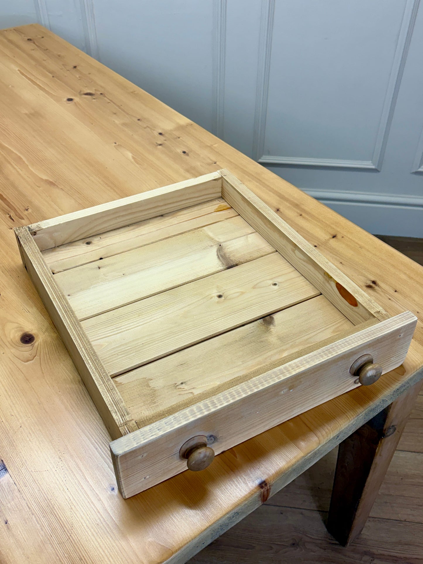 Wooden drawer on a wooden table with a light blue wall in the background