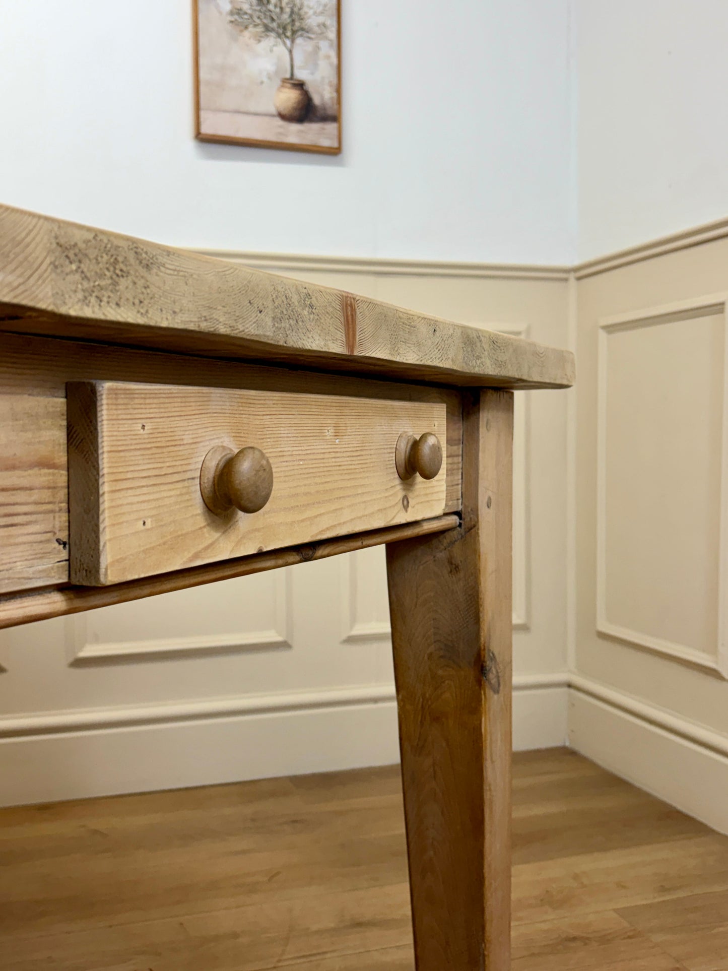 Wooden desk with a drawer in a room with light-colored walls and flooring.