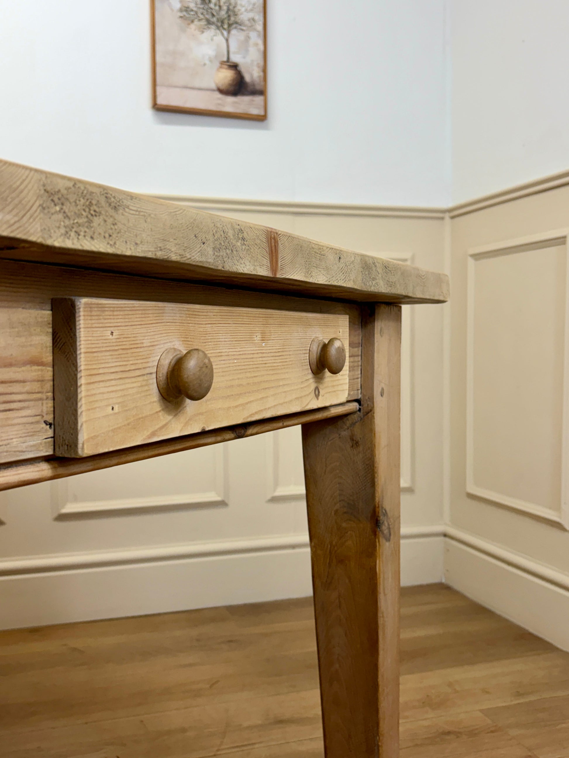 Wooden desk with a drawer in a room with light-colored walls and flooring.