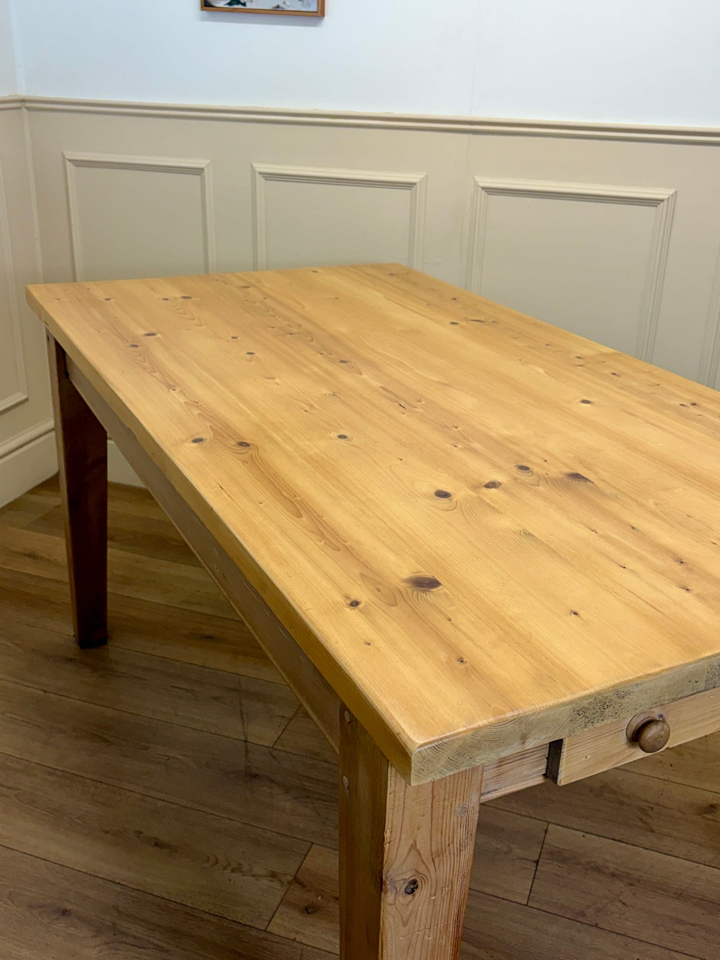 Wooden table in a room with panelled walls and wooden floor.