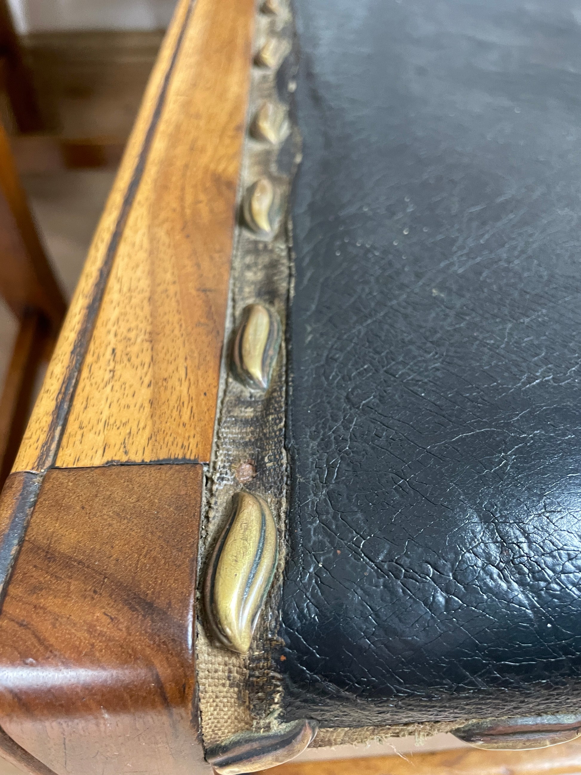 Close-up of a wooden and leather product with metal studs.