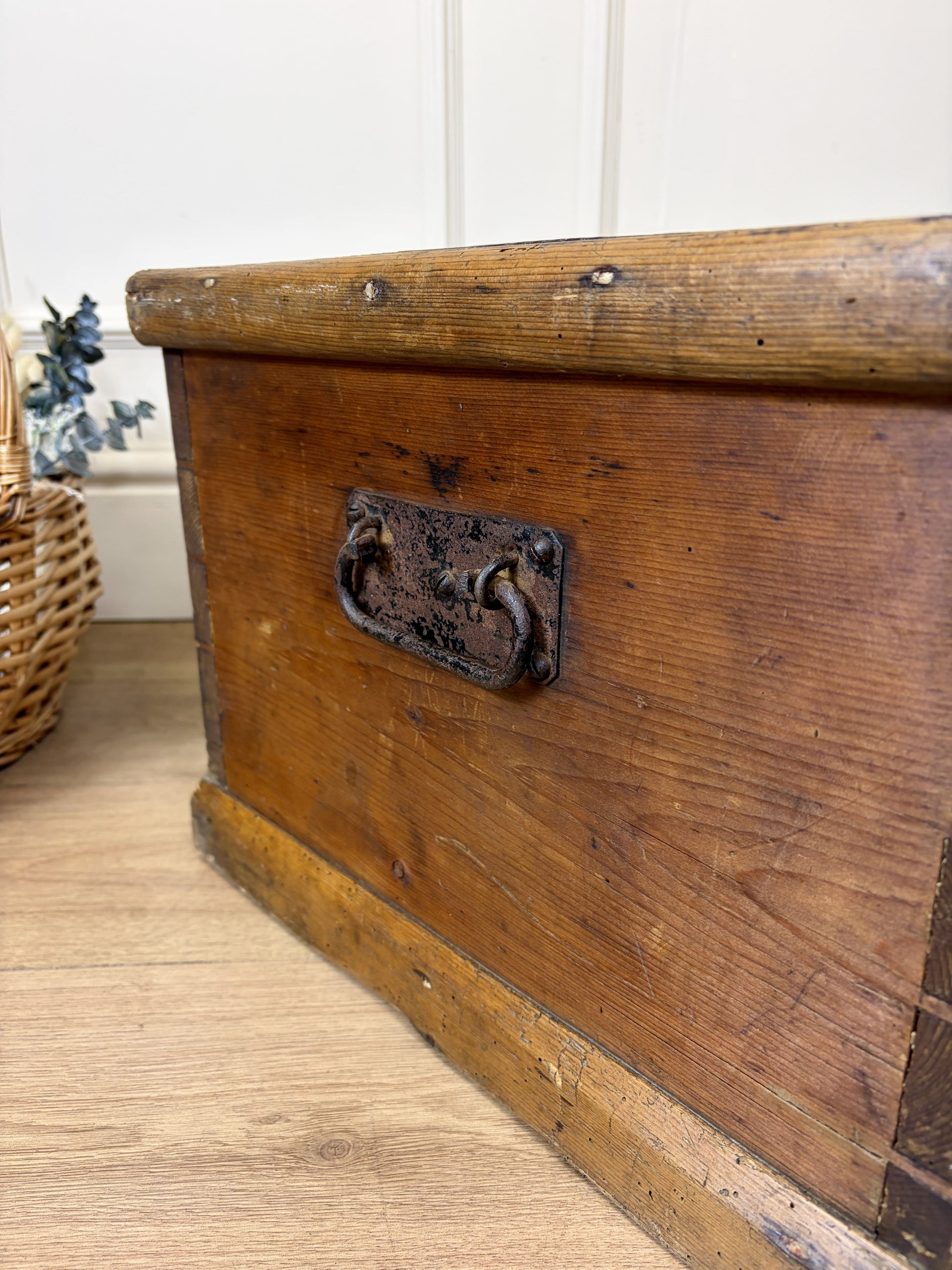 Vintage wooden trunk with a metal handle on a wooden floor.