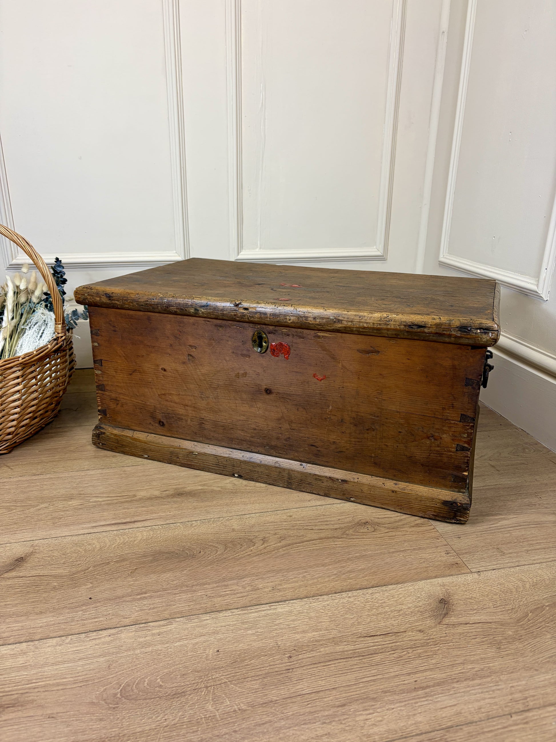 Vintage wooden trunk on a wooden floor with a white paneled wall in the background