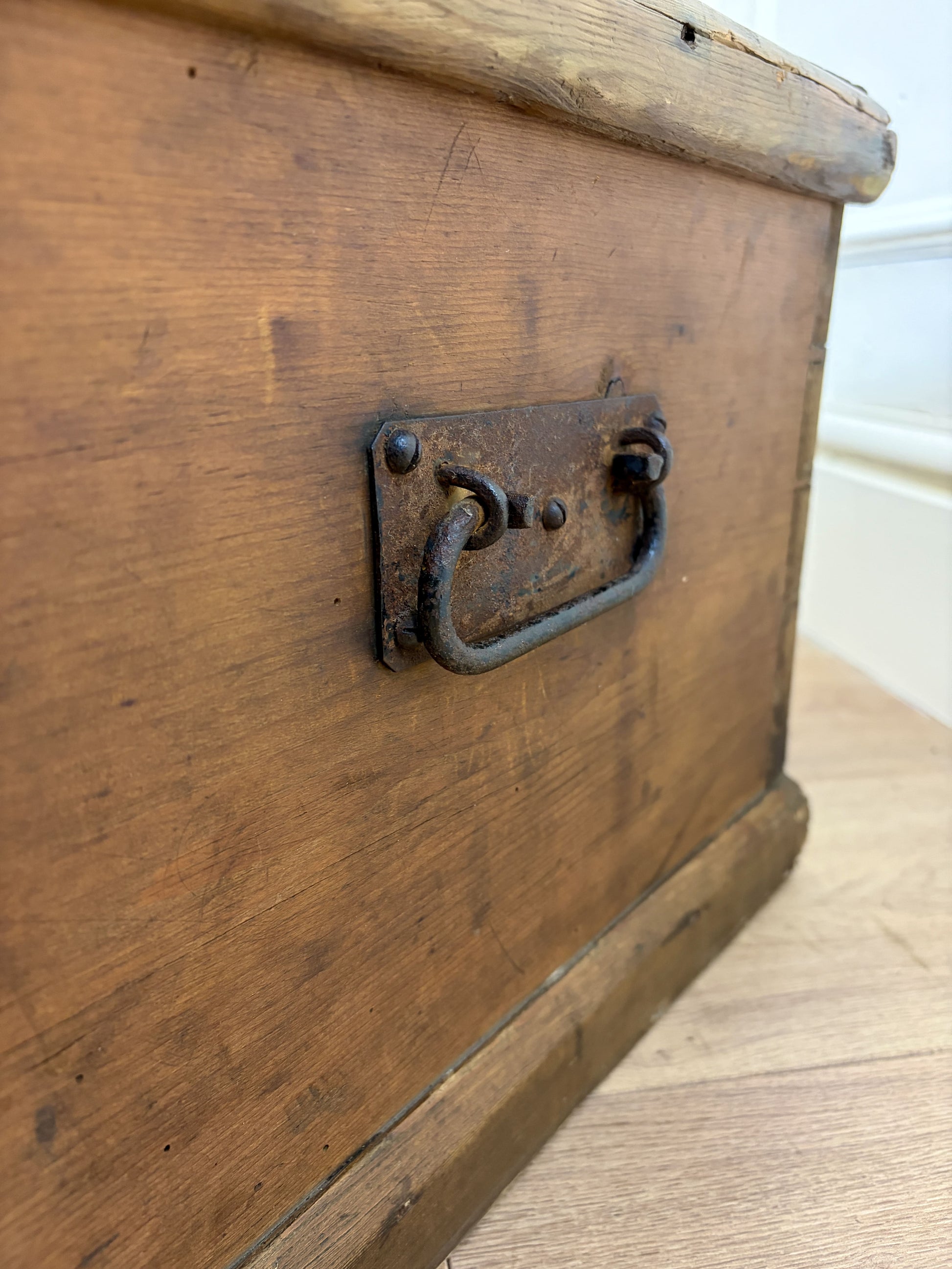 Close-up of an old wooden trunk with a metal handle on a wooden floor.