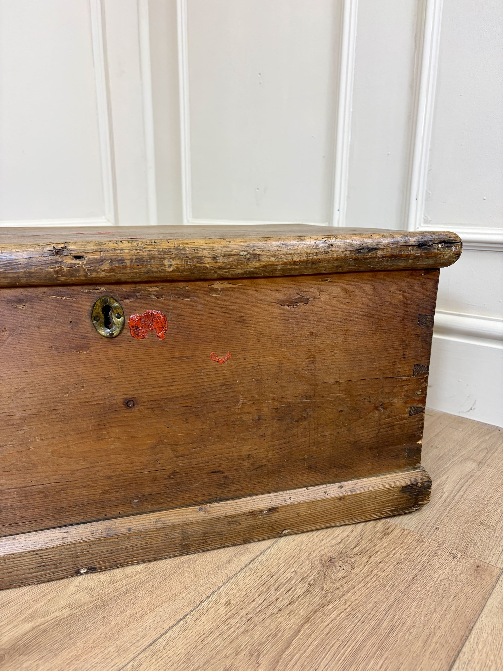 Wooden trunk on a wooden floor with white paneled walls in the background