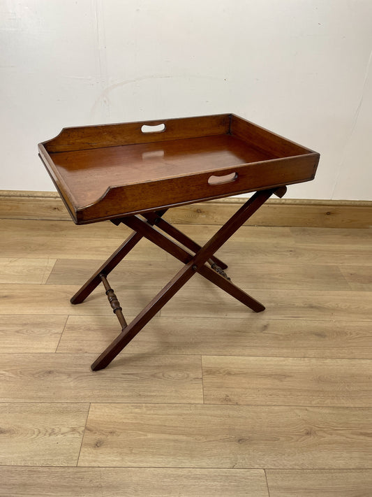 Wooden tray table on a wooden floor with a white wall background