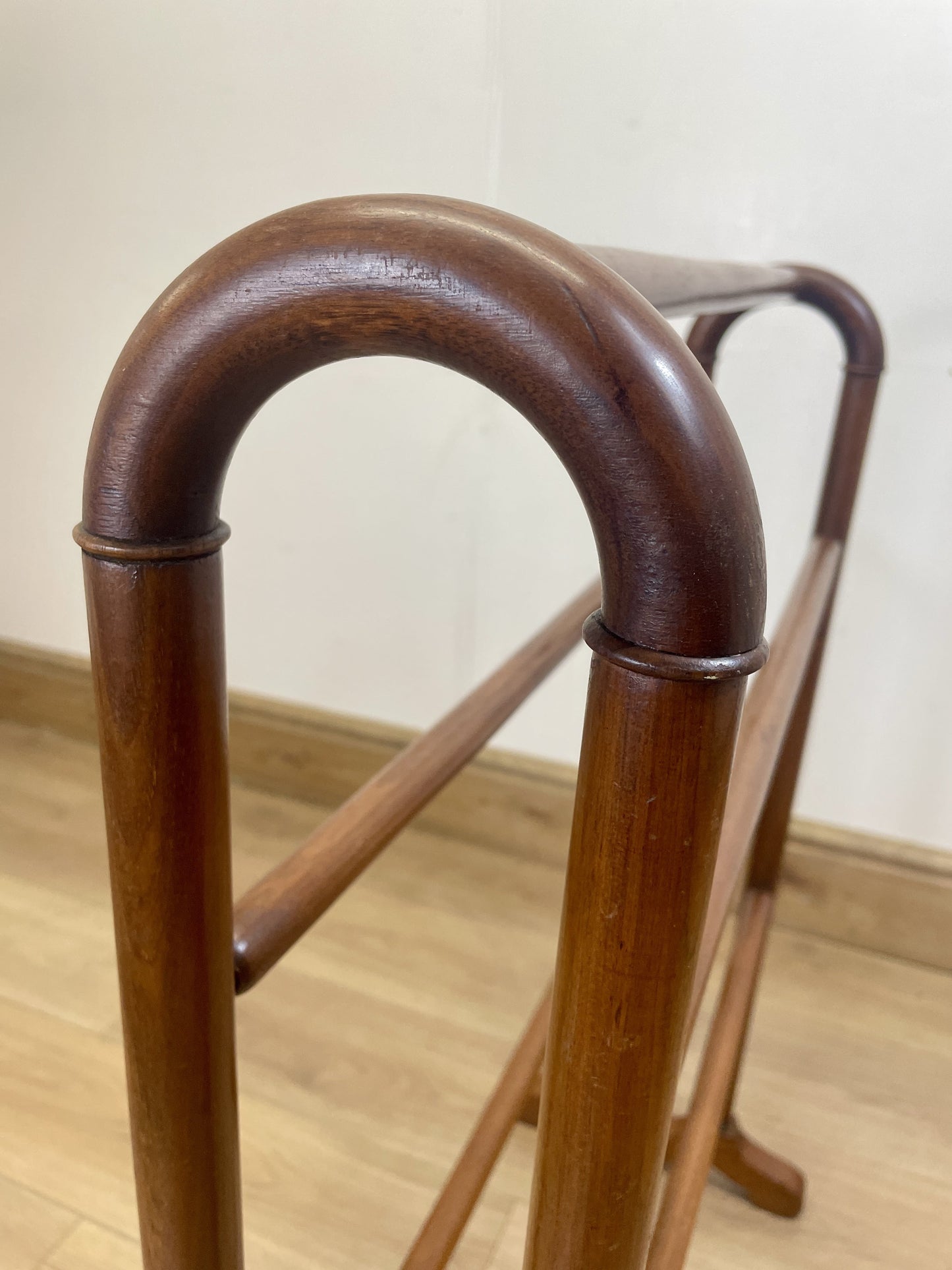 Wooden walking cane on a wooden floor with a neutral wall background