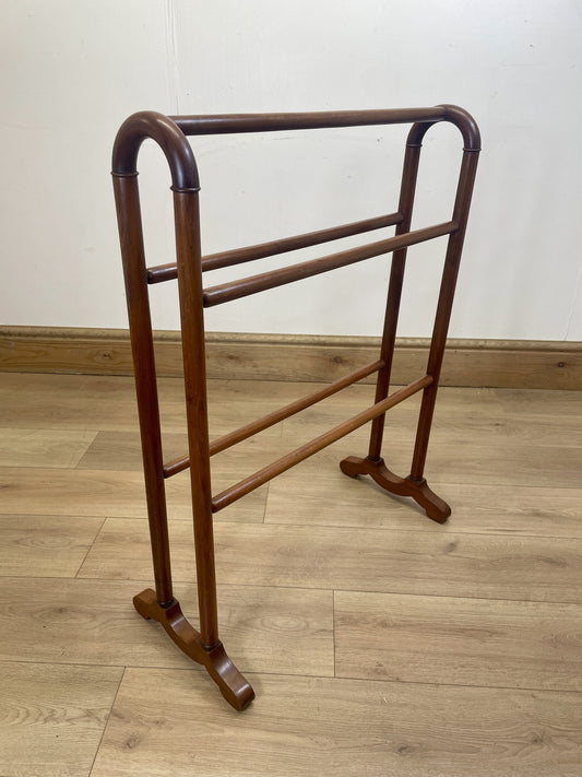 Wooden towel rack on a wooden floor with a white wall background