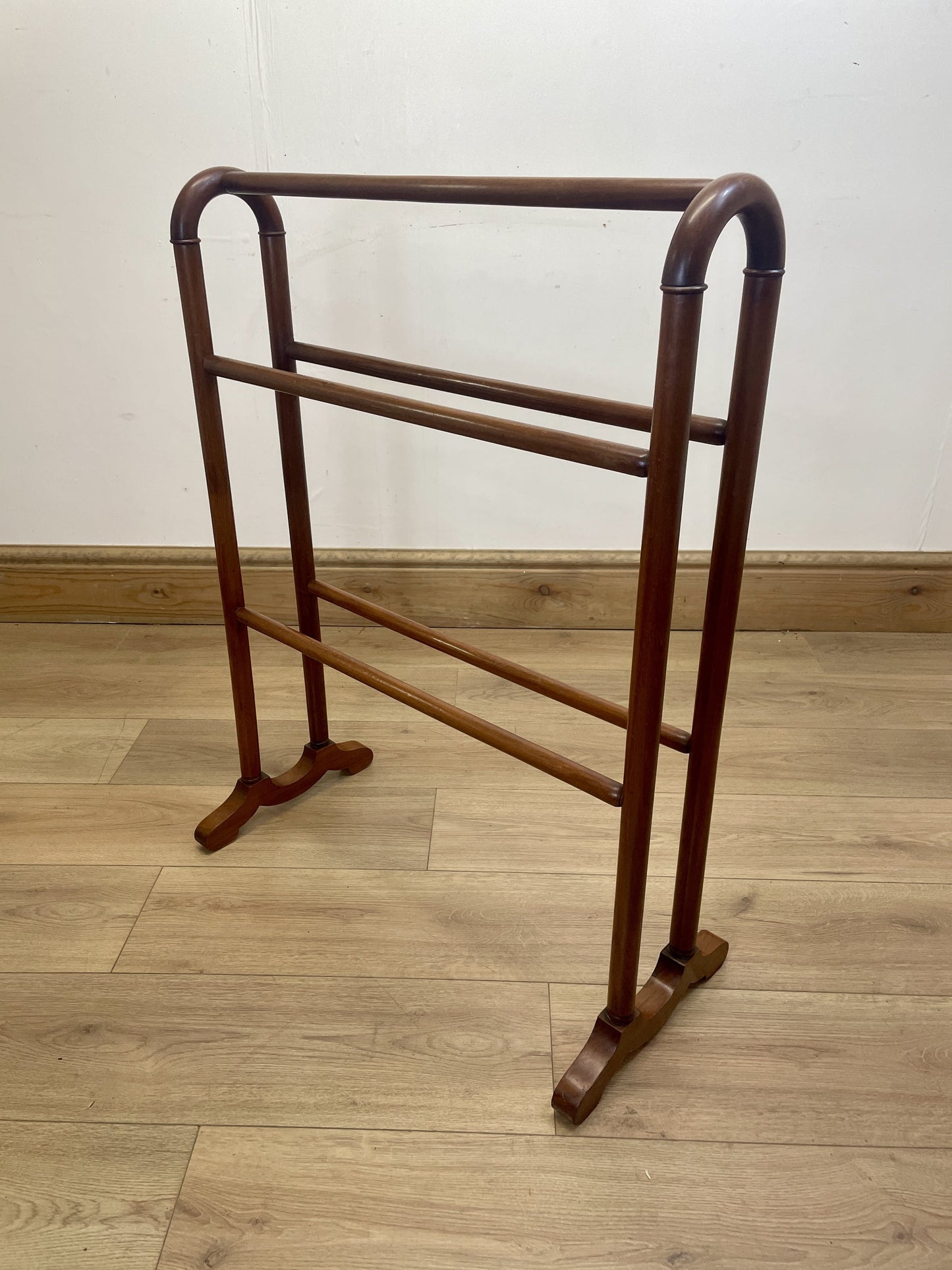 Wooden towel rack on a wooden floor with a white wall background
