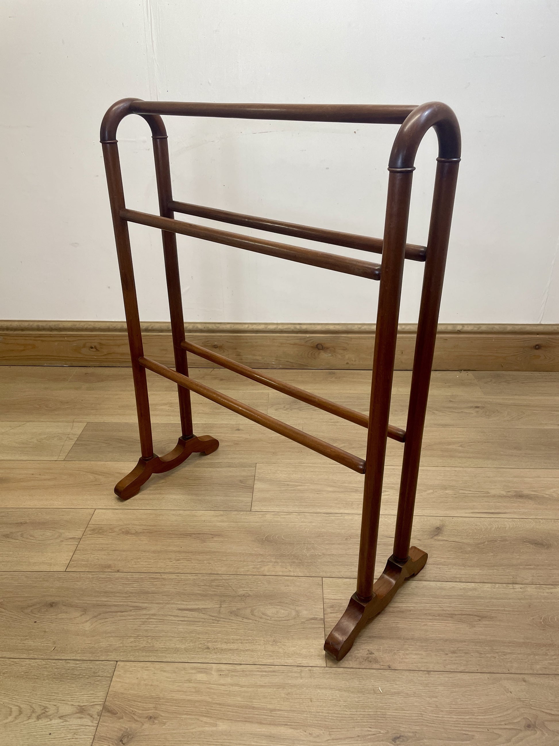 Wooden towel rack on a wooden floor with a white wall background