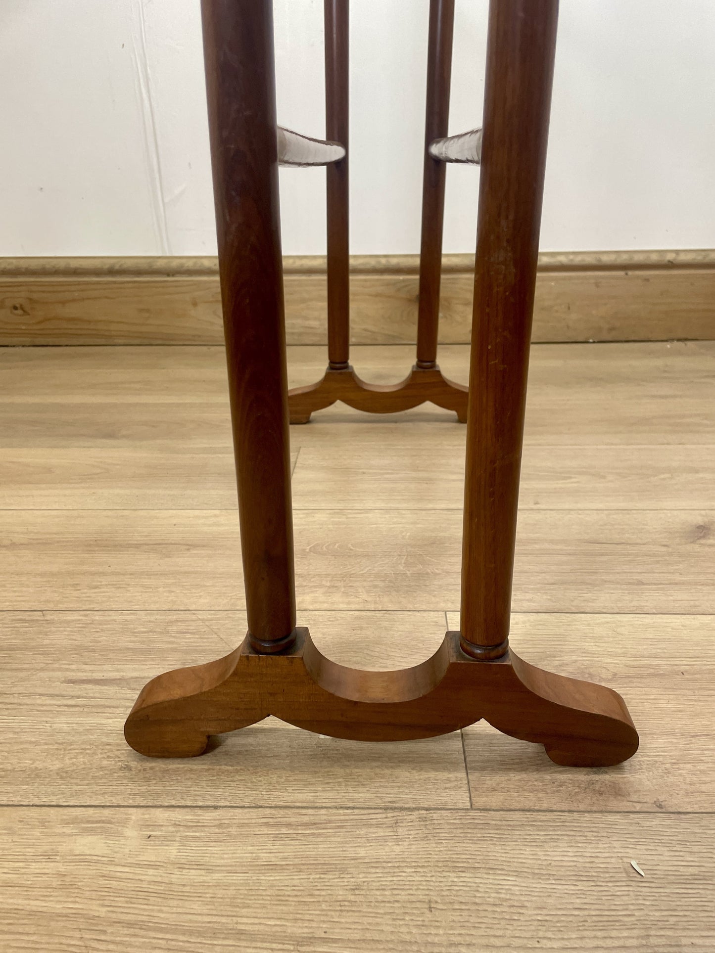 Wooden stand with three vertical bars on a wooden floor.