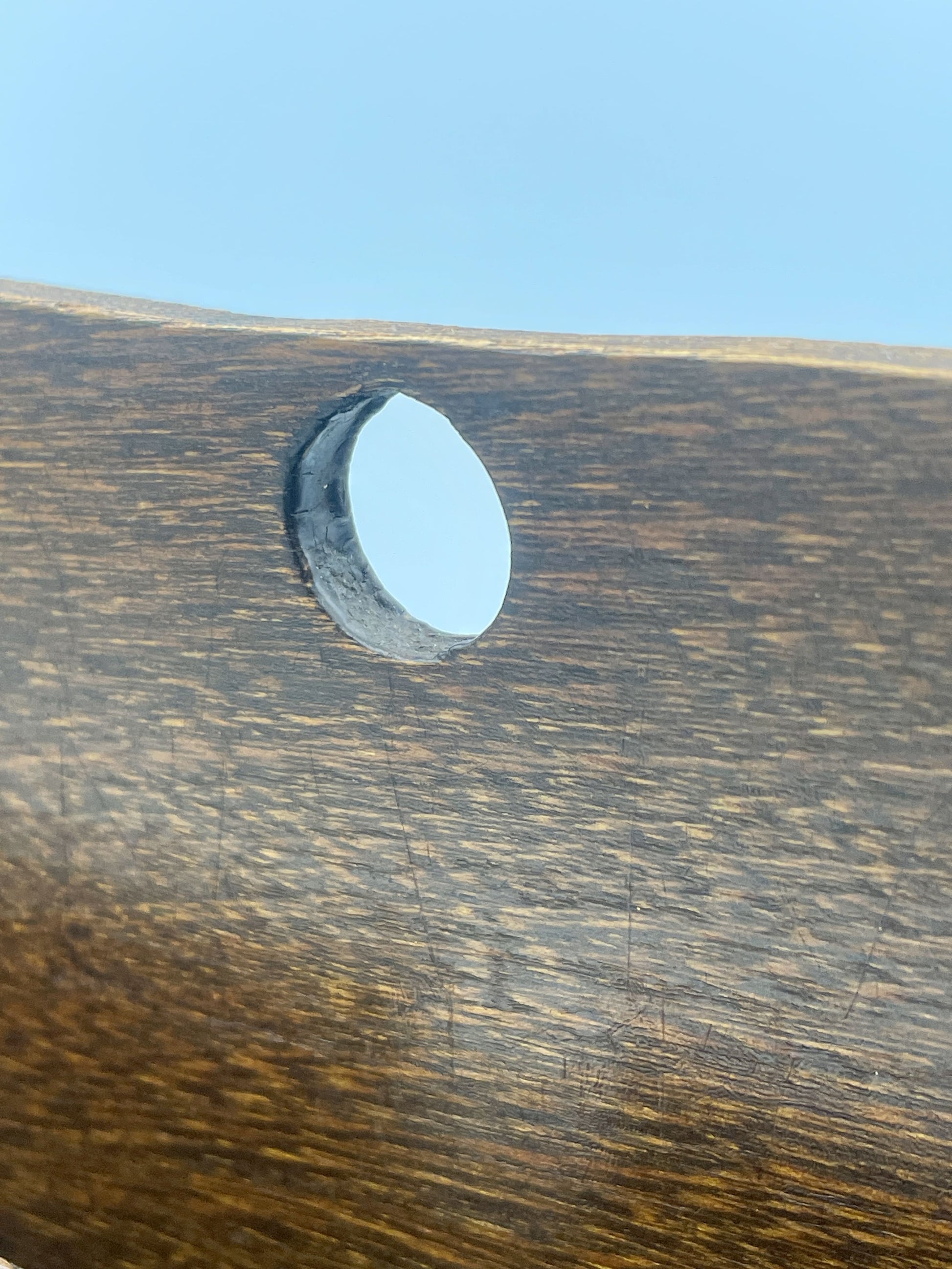 Wooden surface with a circular hole against a blue sky background