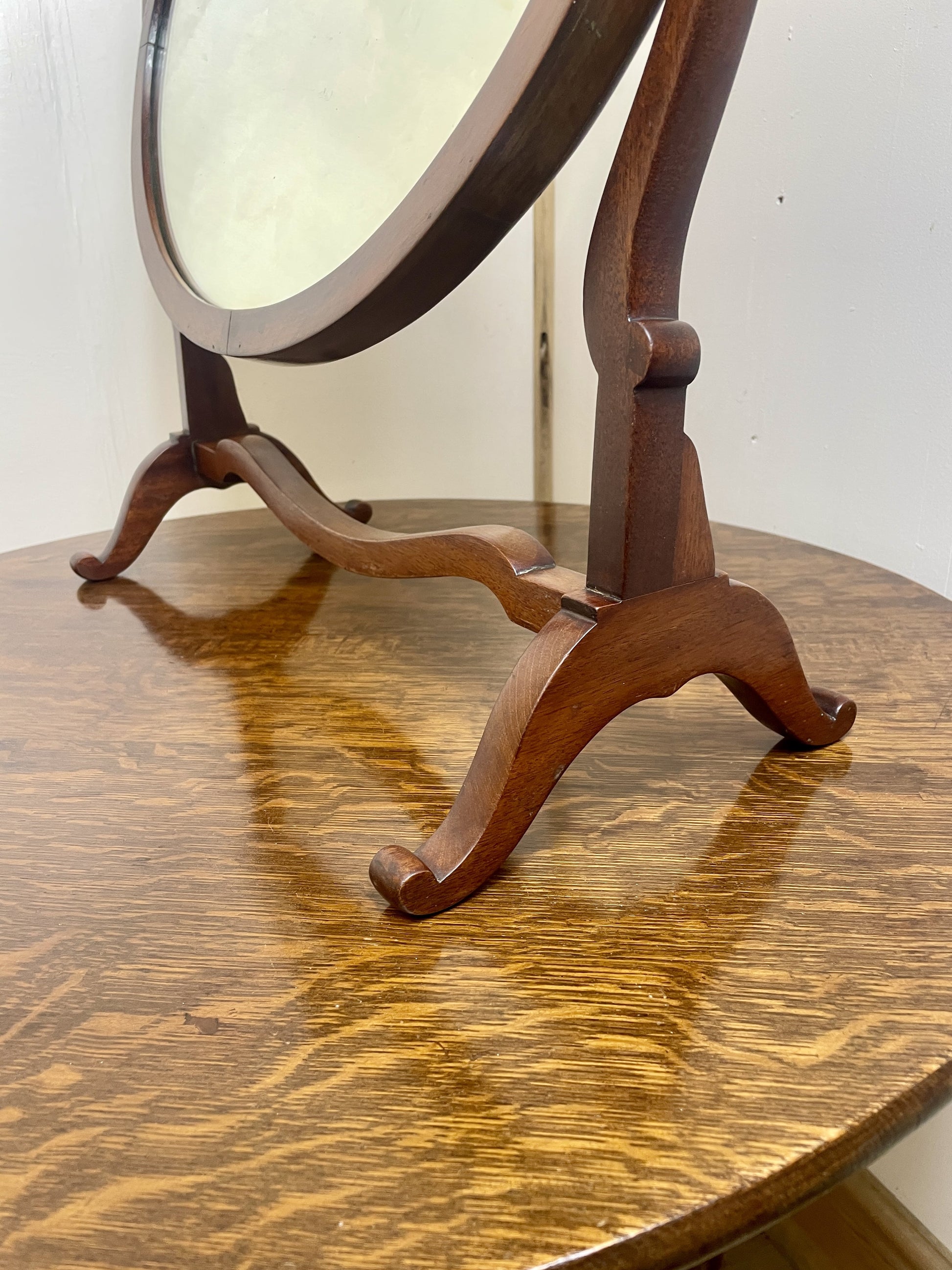 Wooden stand with round mirror on a wooden surface