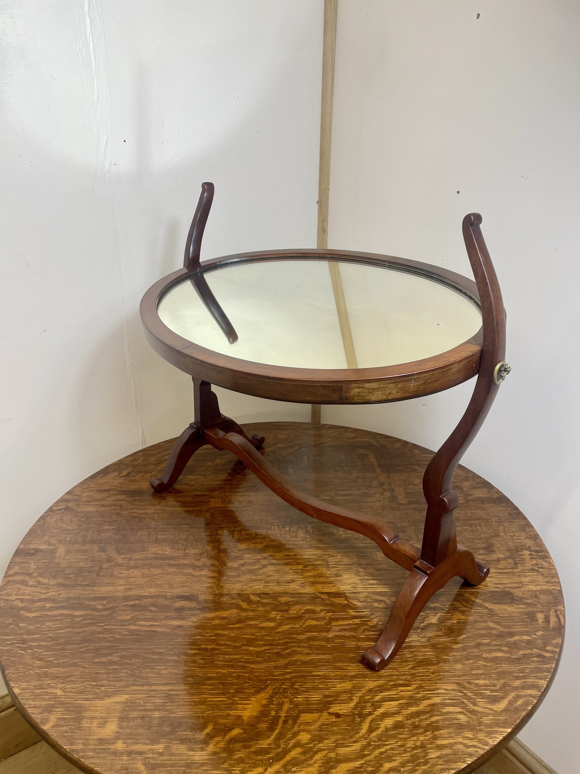 Round wooden table with glass top against a white wall