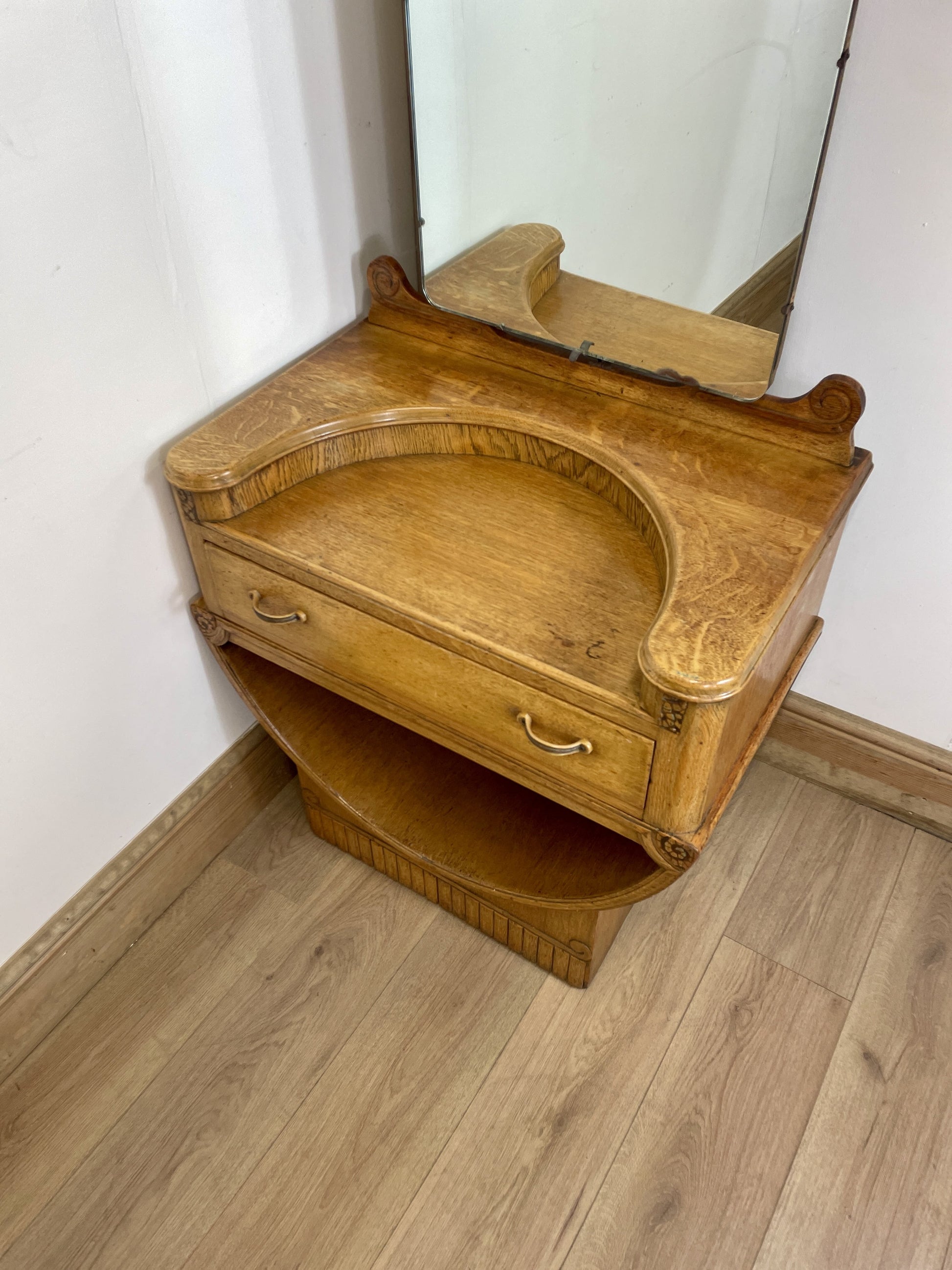 Wooden vanity with mirror on a wooden floor against a white wall