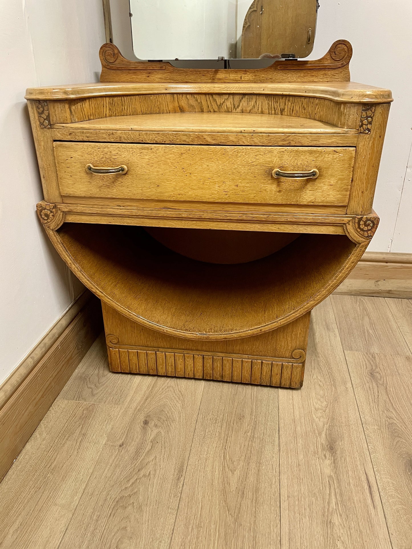 Wooden dresser with a mirror on top in a room with wooden flooring.