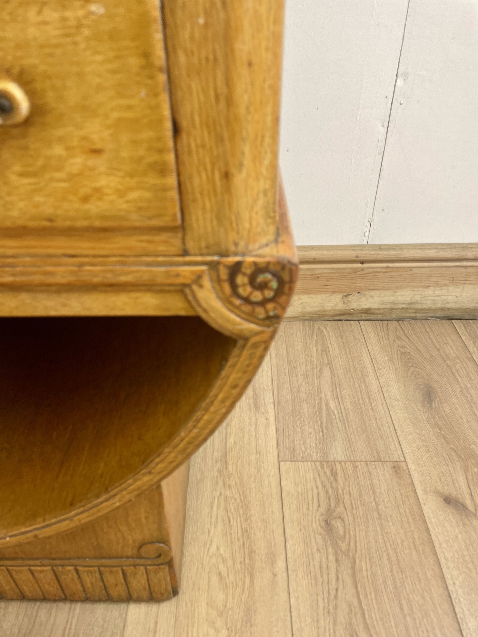 Wooden side table with a decorative carvings on a wooden floor.