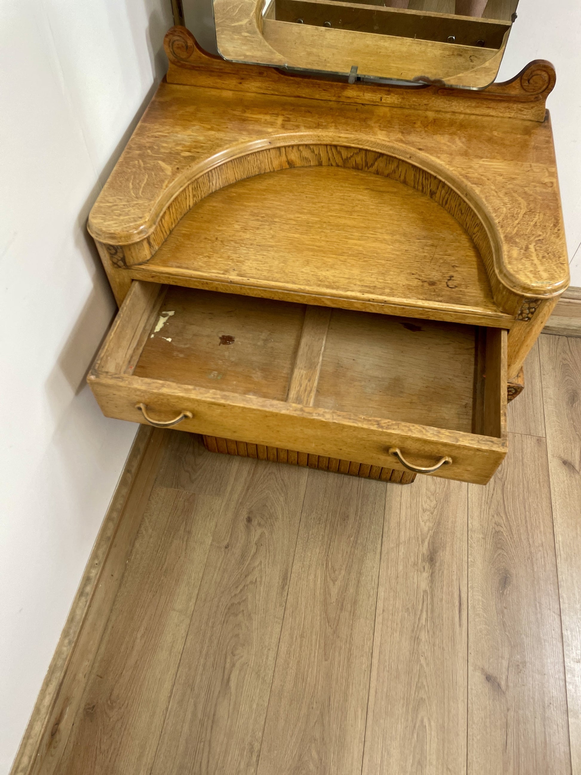 Wooden corner cabinet with an open drawer on a wooden floor.