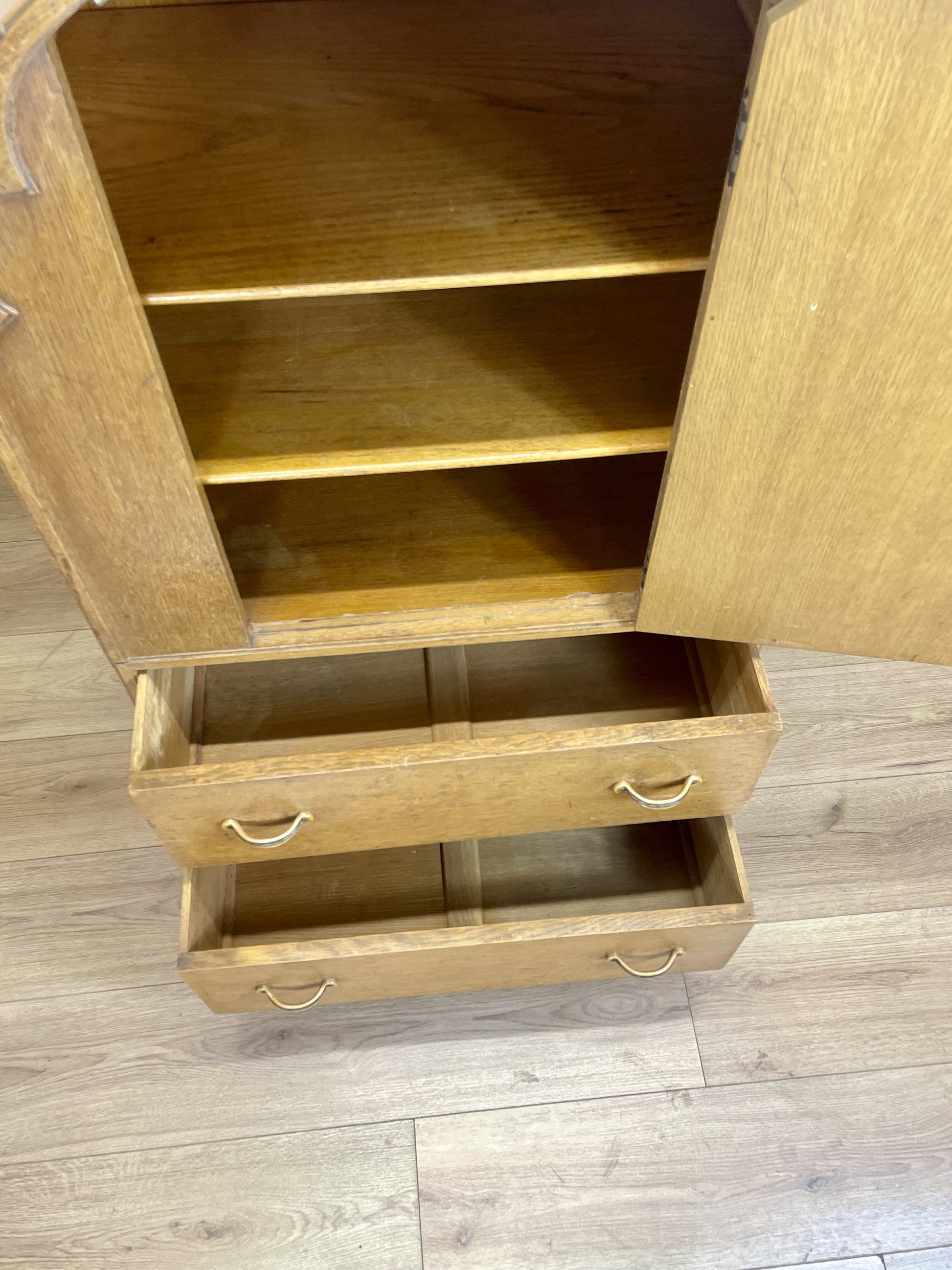 Wooden cabinet with open doors and drawers on a wooden floor