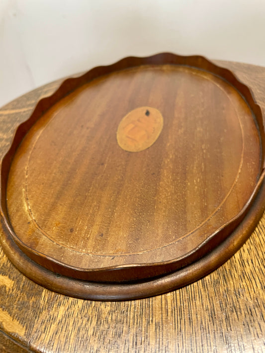Wooden tray with a central circular emblem on a wooden surface