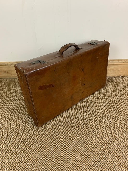 Vintage brown leather suitcase with a metal frame and a fabric handle.