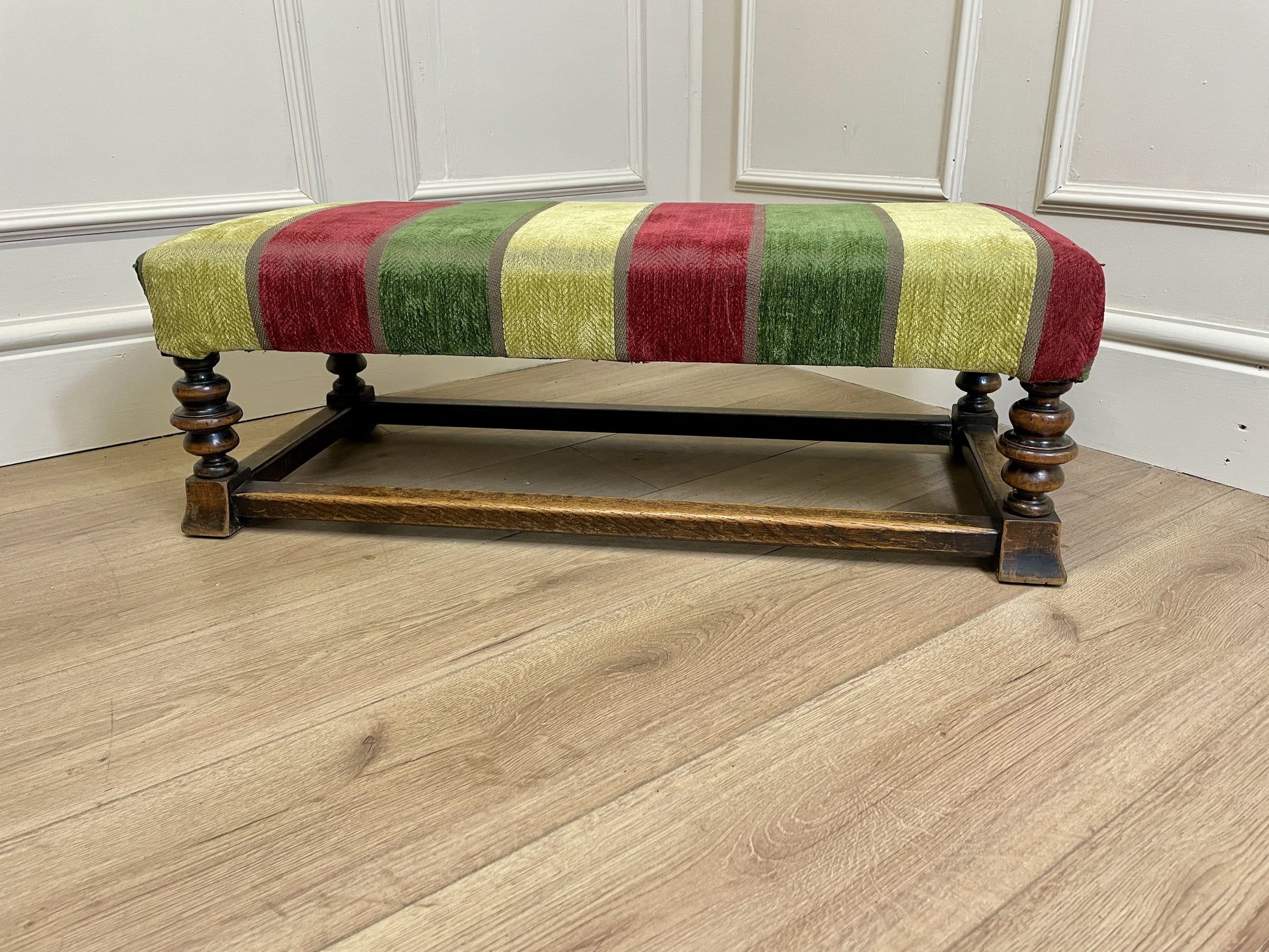 Vintage solid oak long low footstool with multicoloured upholstery and turned legs. Restored, sturdy and full of charm – a perfect accent for any living space.