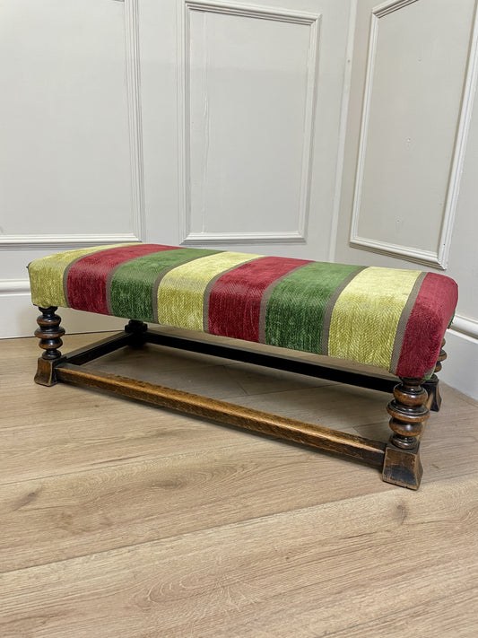 Vintage solid oak long low footstool with multicoloured upholstery and turned legs. Restored, sturdy and full of charm – a perfect accent for any living space.
