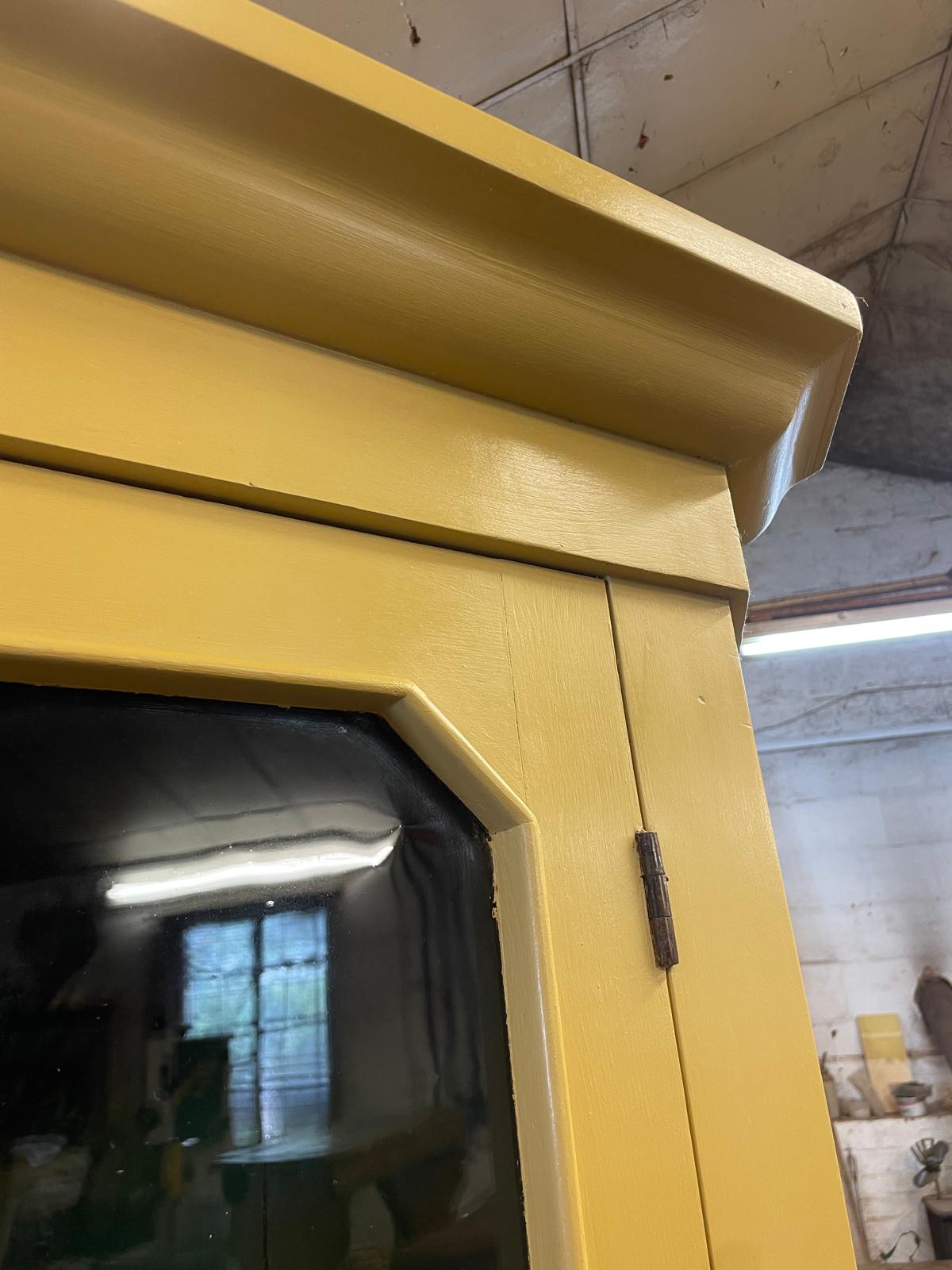 Yellow fireplace with a glass door in a room with concrete walls.