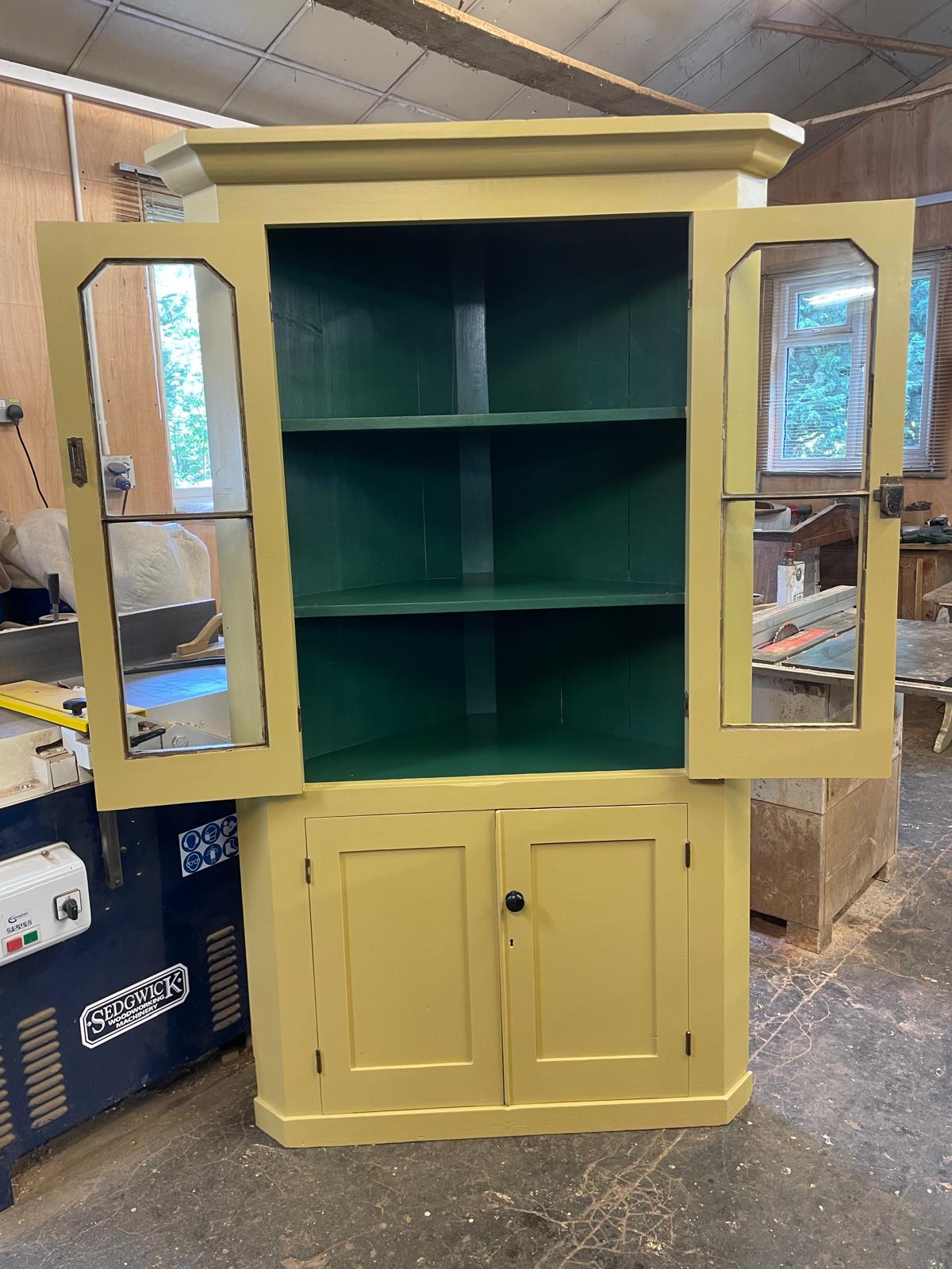 Yellow cabinet with glass doors in a workshop setting