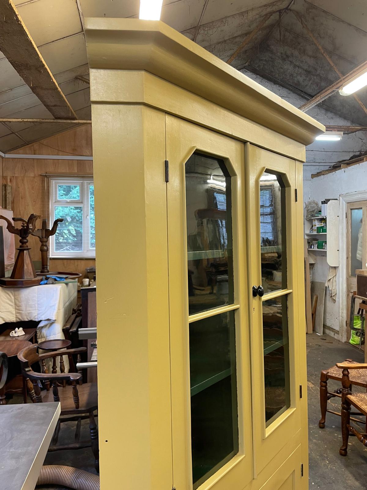 Yellow cabinet with glass doors in a workshop setting