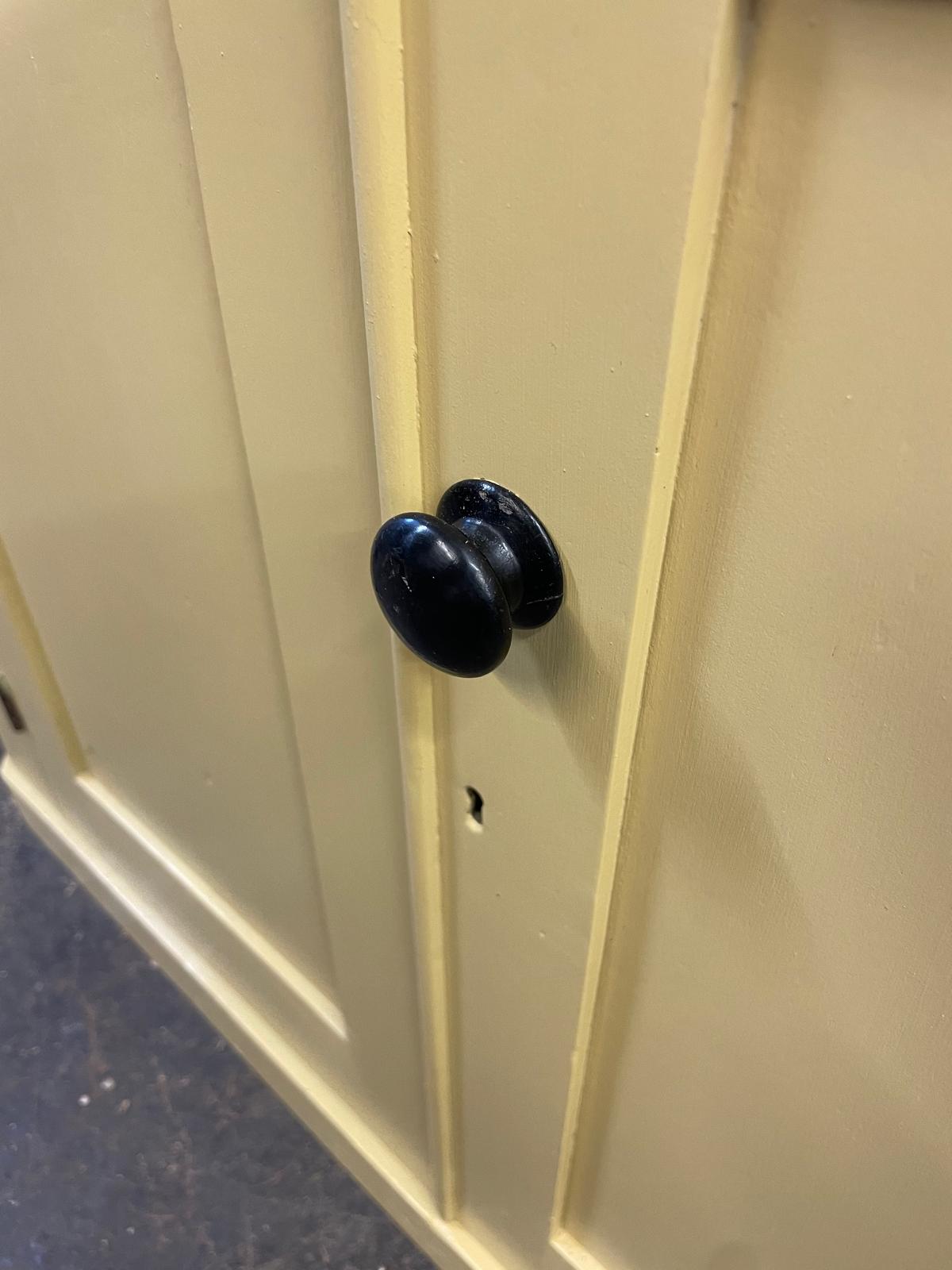 Beige cabinet with a black knob on a plain background