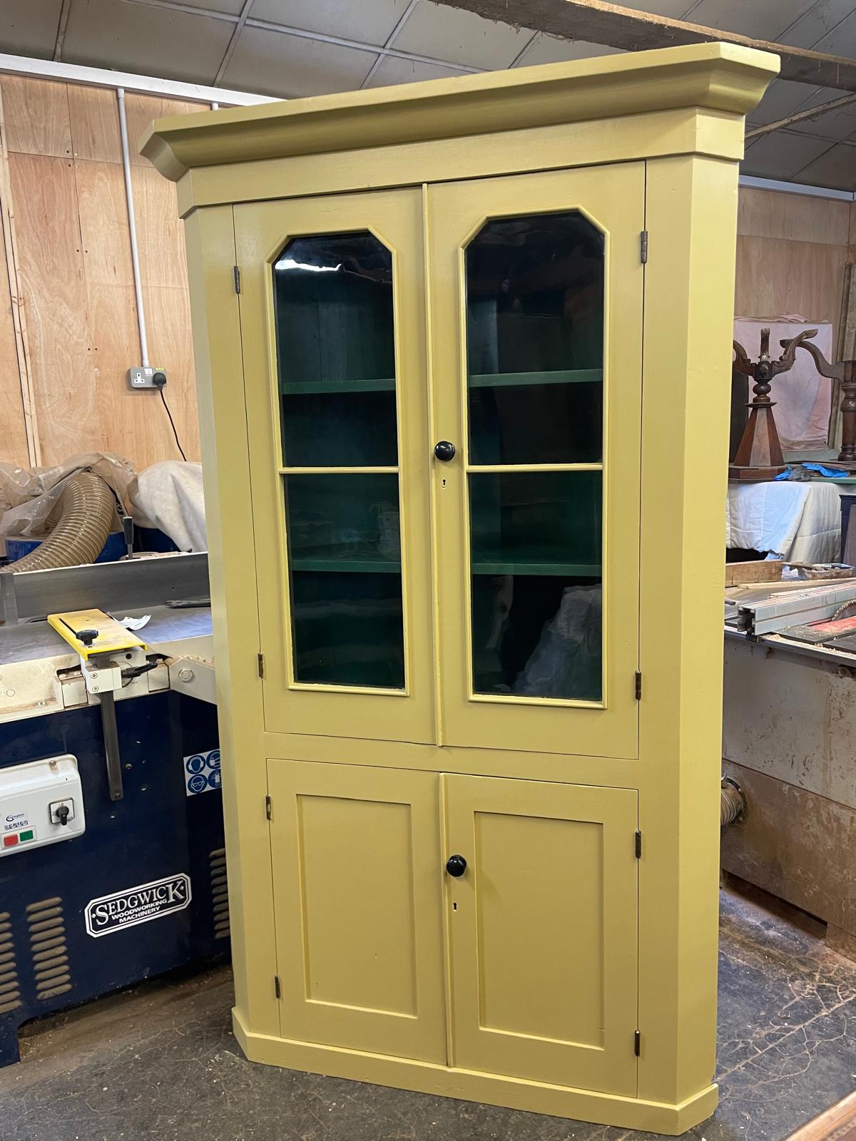 Yellow cabinet with glass doors in a workshop setting