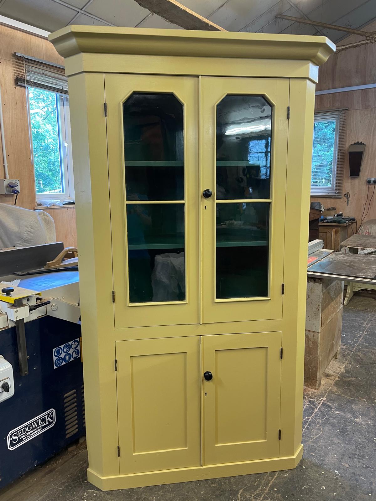 Yellow cabinet with glass doors in a workshop setting