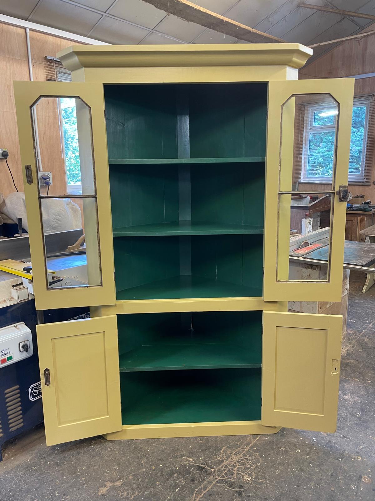 Green cabinet with yellow doors in a workshop setting
