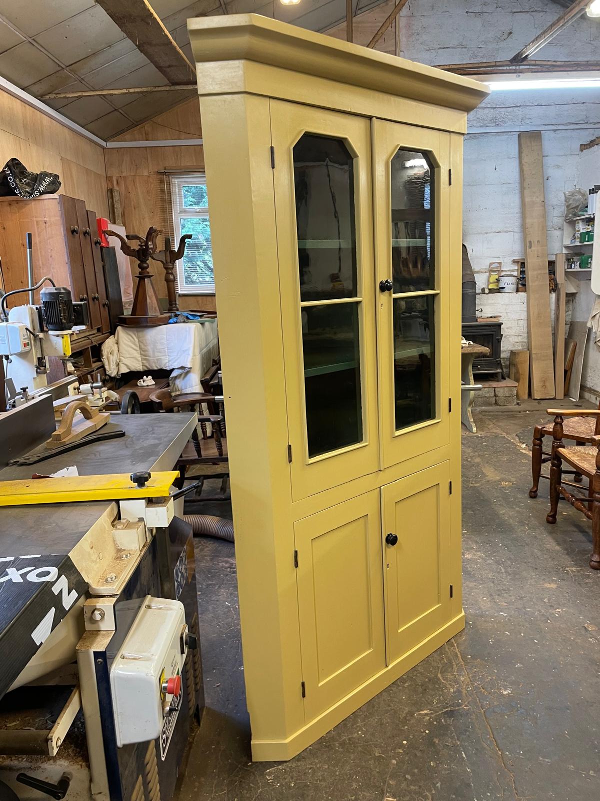 Yellow cabinet with glass doors in a workshop setting
