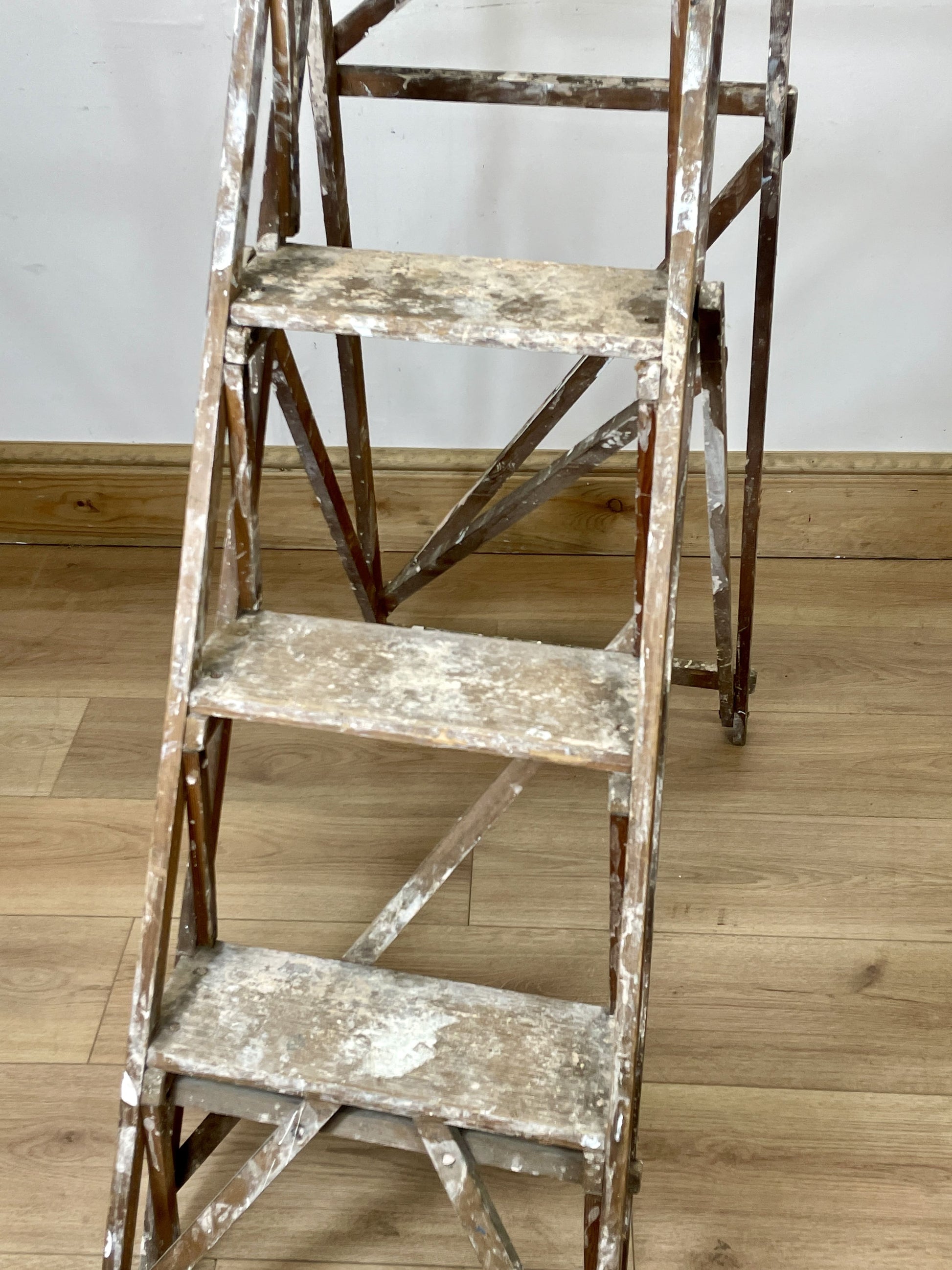 Two old wooden ladders on a wooden floor with a white wall background