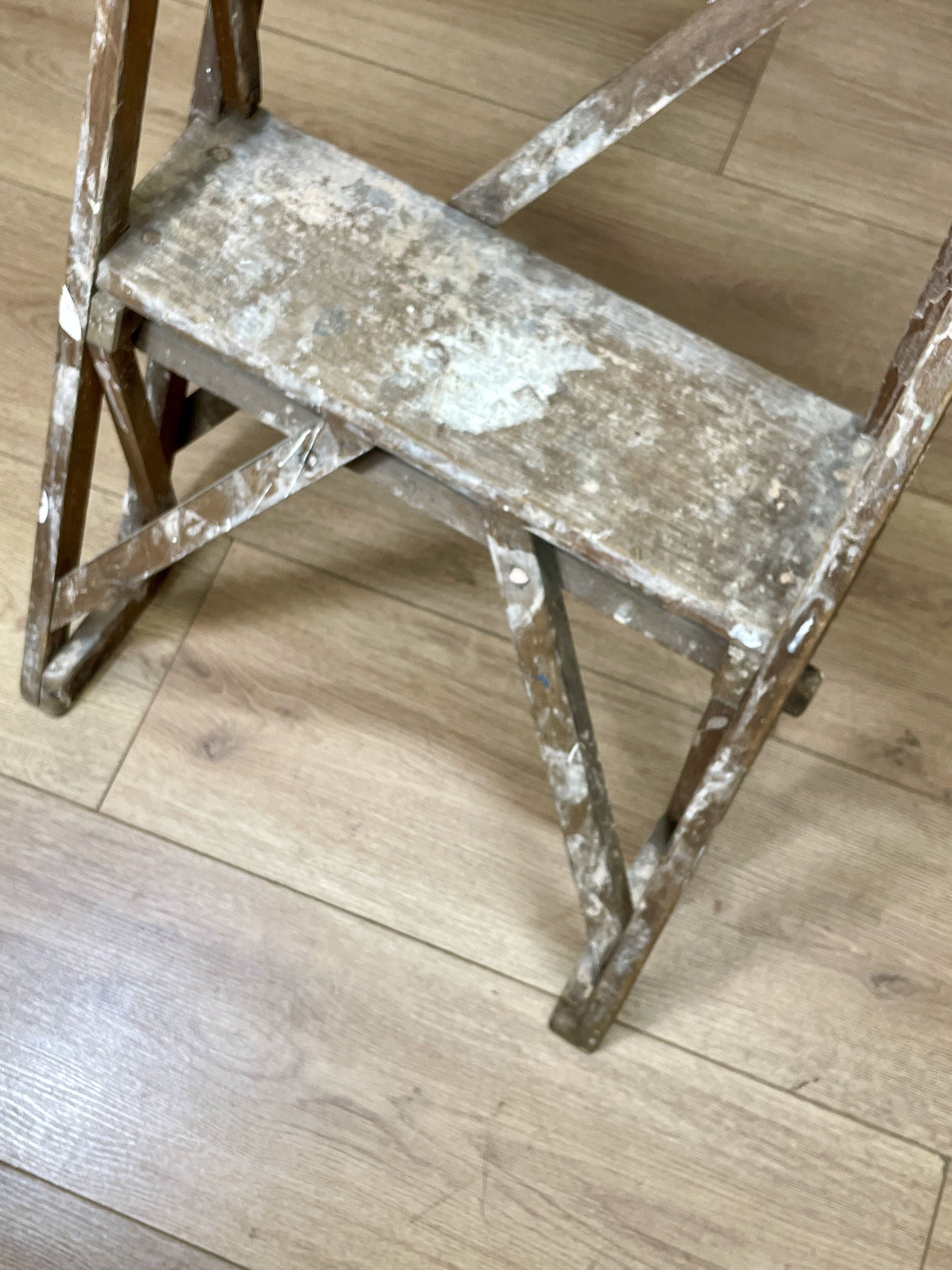Worn metal step ladder on a wooden floor
