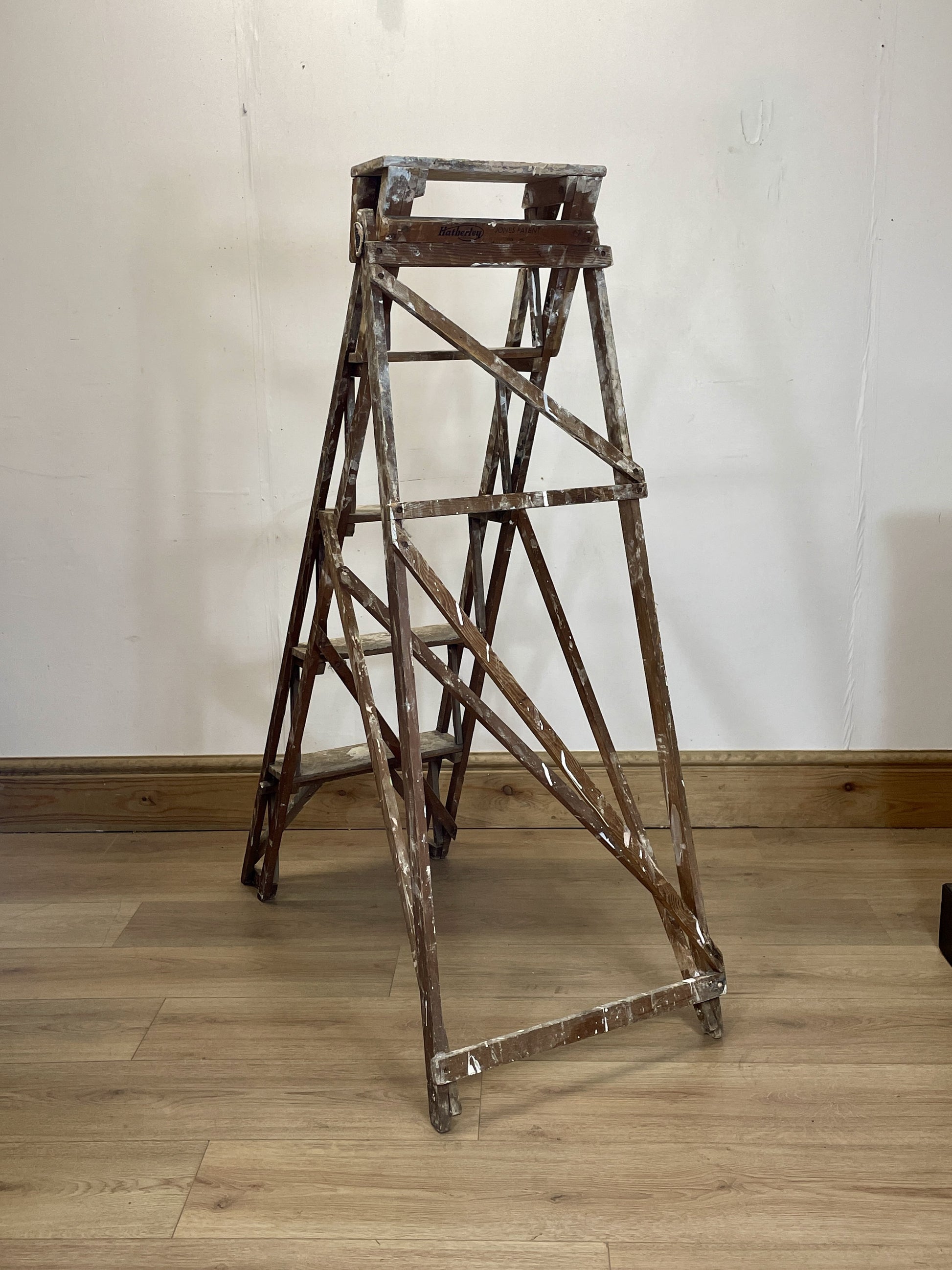 Vintage wooden step ladder on a wooden floor with a white wall background