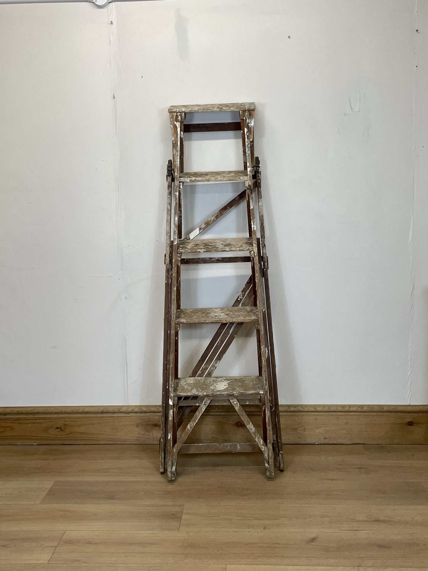 Wooden ladder against a white wall on a wooden floor