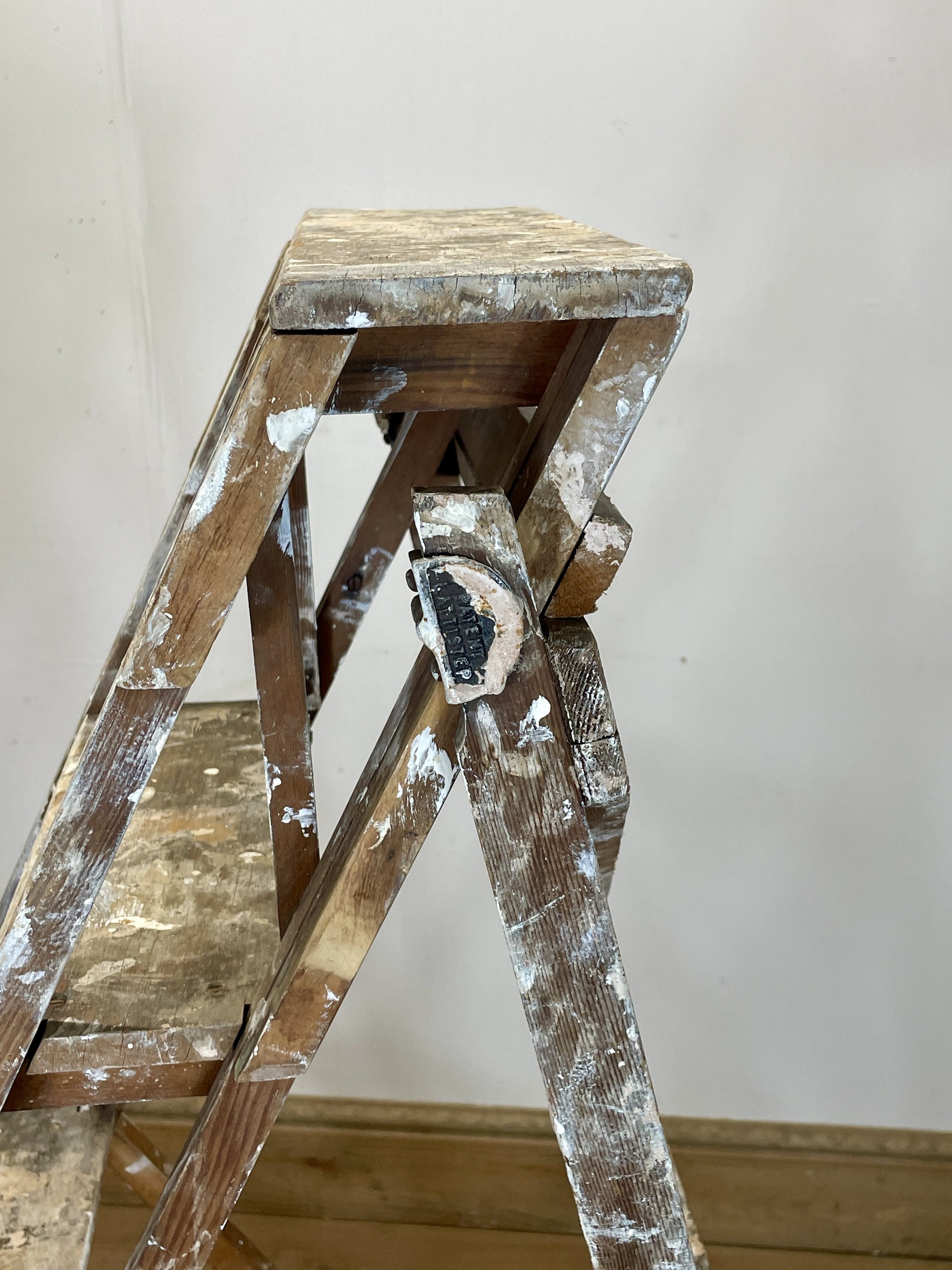 Worn wooden step ladder against a plain wall