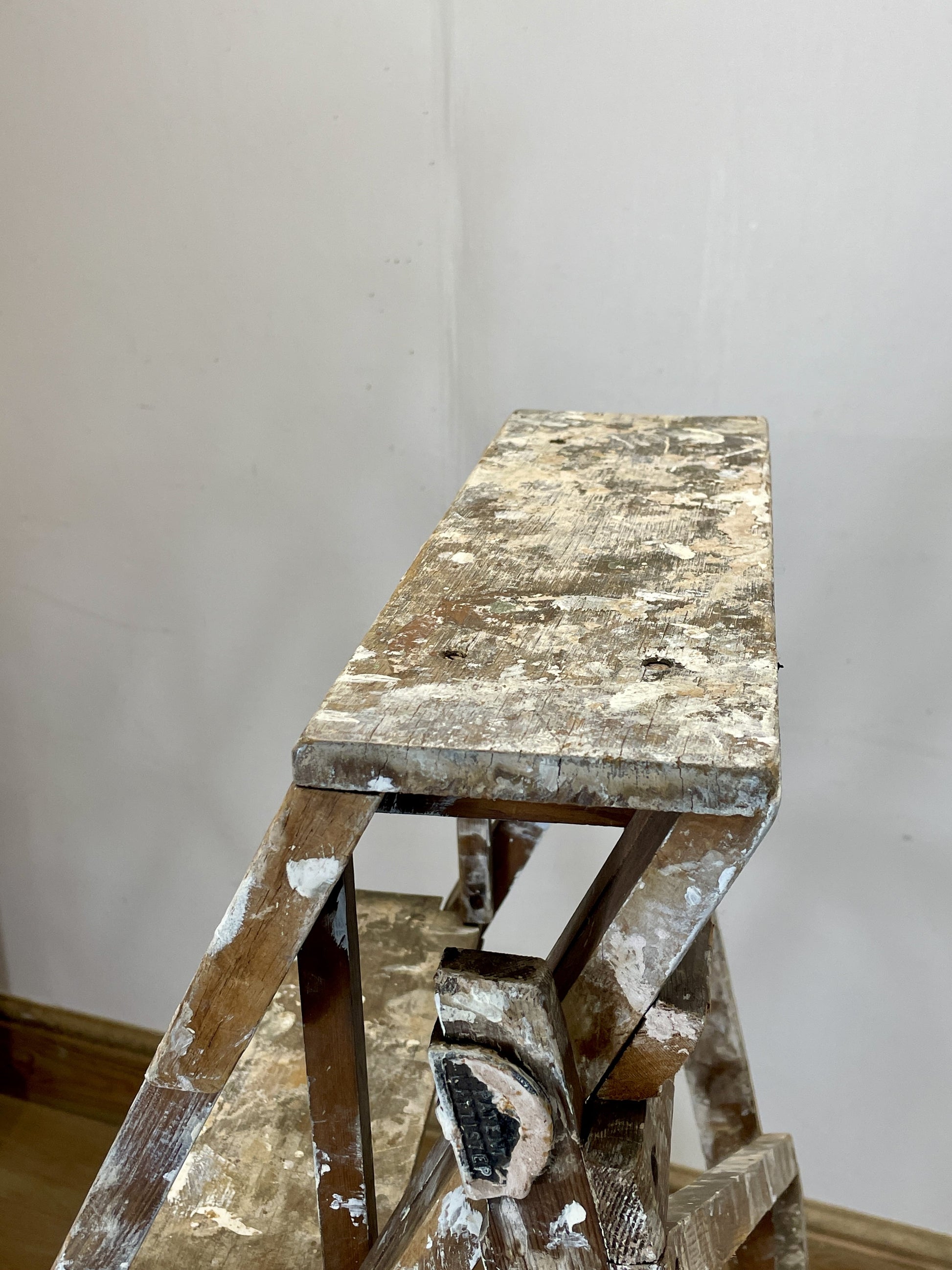 Worn wooden ladder against a plain white wall